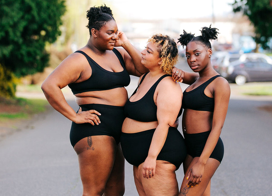 Three different sized models wearing Thunderpants Organic Cotton Original underwear and Bralettes in plain Black color.