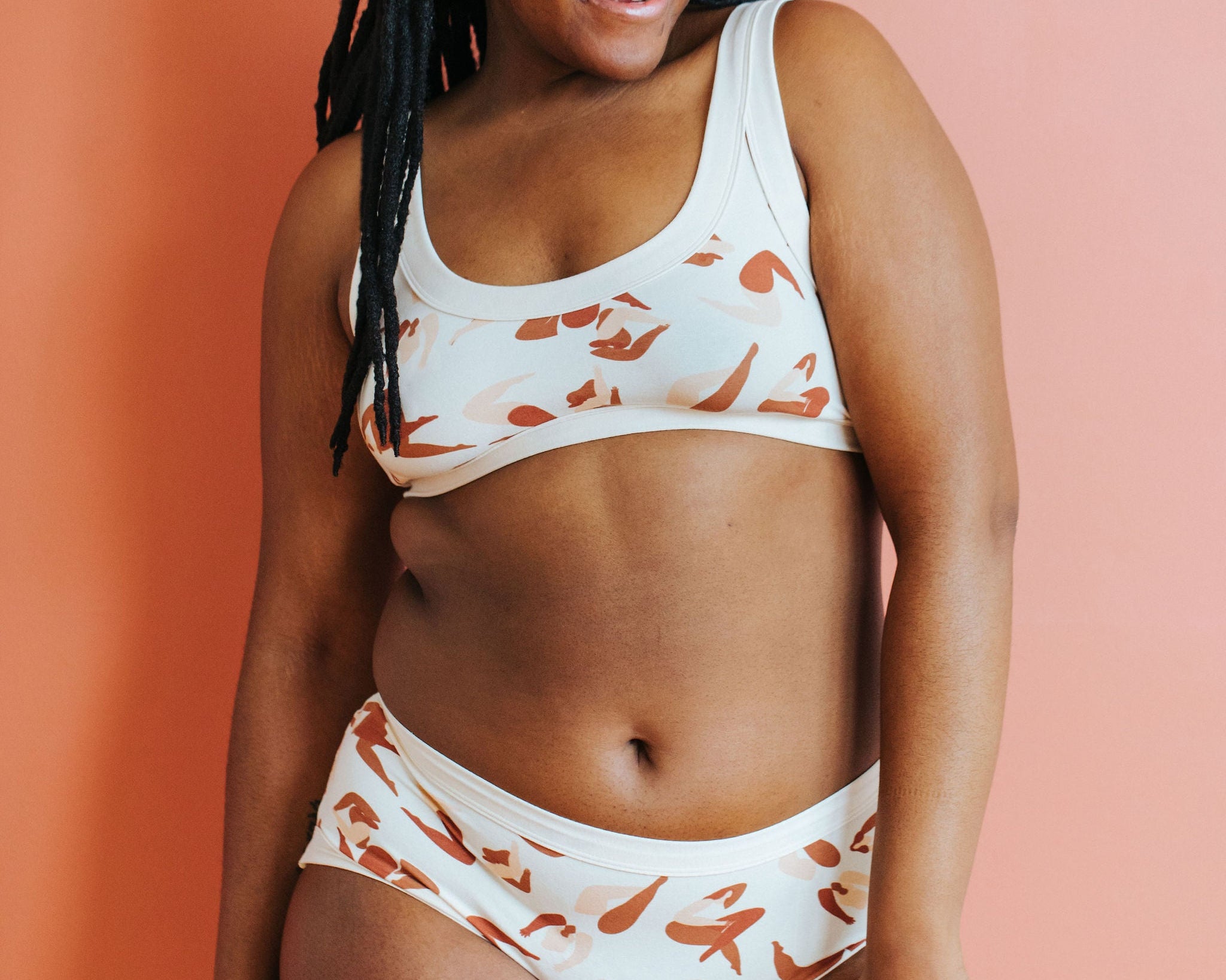 Model smiling wearing Thunderpants Hipster style underwear and Bralette in Bodies in Motion: women in different shades of browns and tans.
