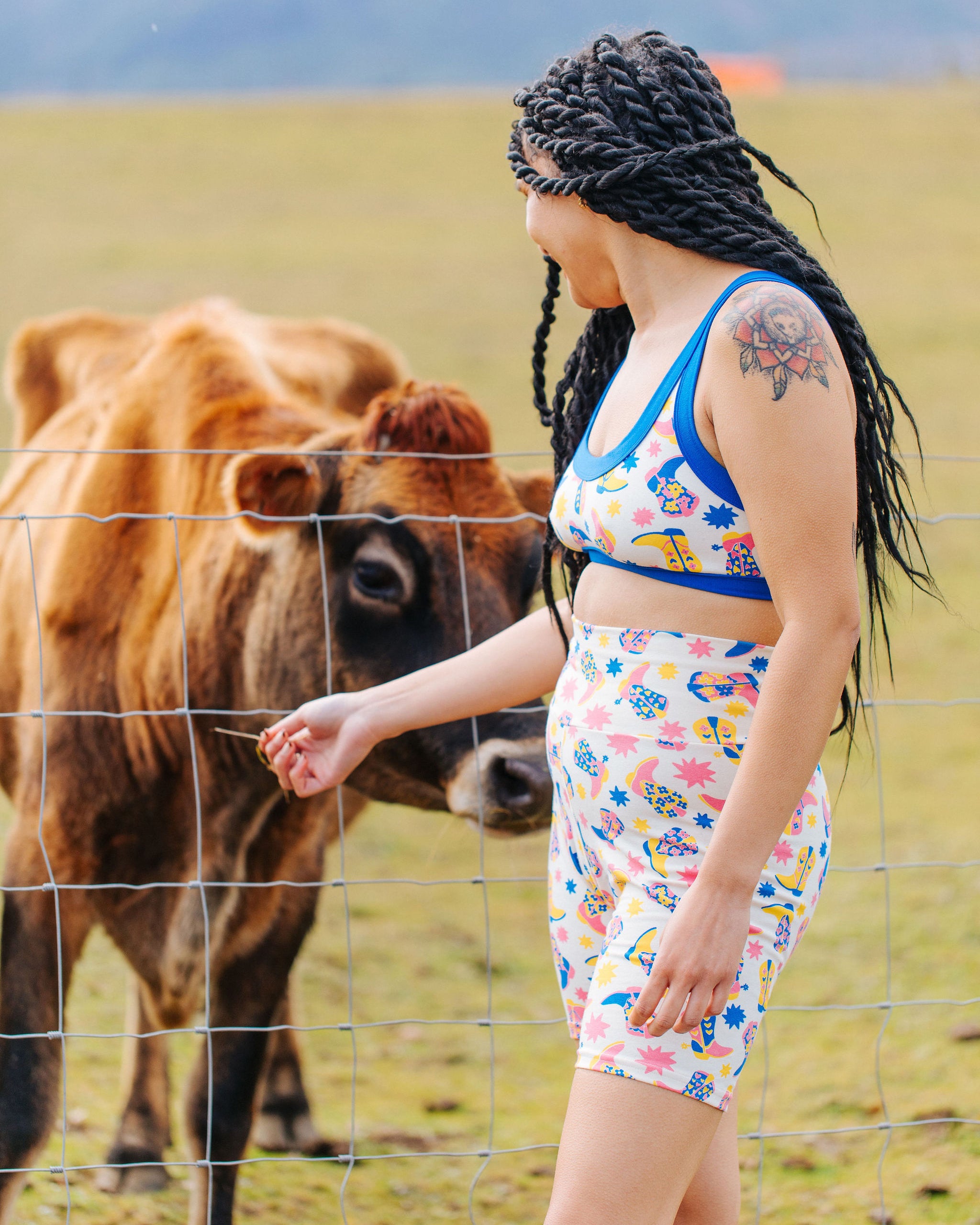 Model with a cow wearing Thunderpants Bike Shorts and Bralette in Boot Scootin' - fun boots in pink, yellow, and blue.