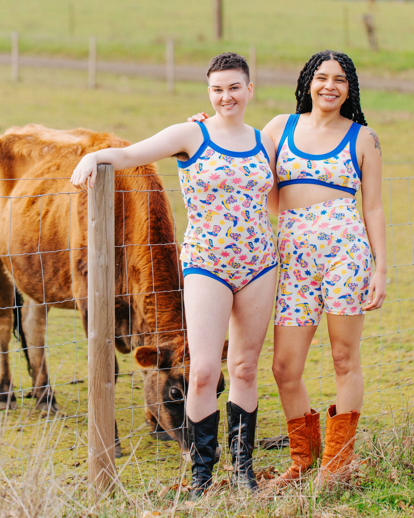 Models in a field with cows wearing Thunderpants multiple style sets in Boot Scootin' - fun boots in pink, yellow, and blue.