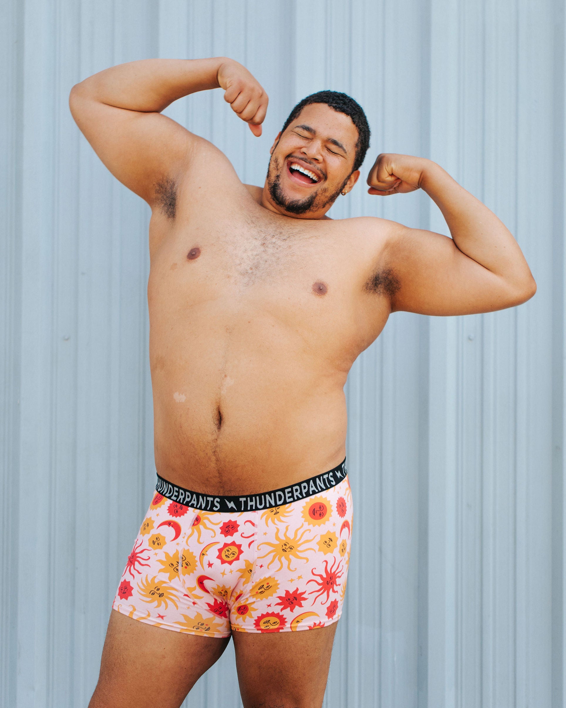 Model wearing Thunderpants Boxer Brief style underwear in Luna y Sol print - pink, yellow, and orange suns and moons.
