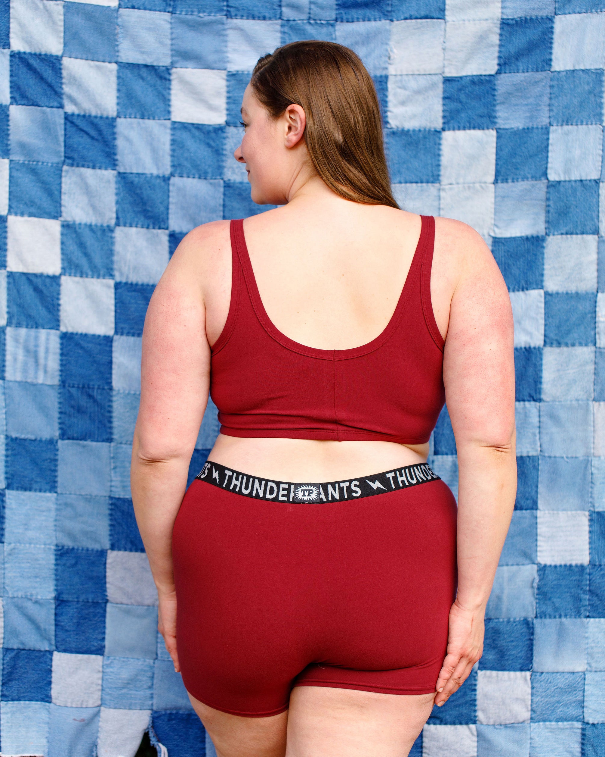 Model wearing Thunderpants Boxer Brief style underwear and Longline Bra in Cabern-YAY - a deep wine red color.