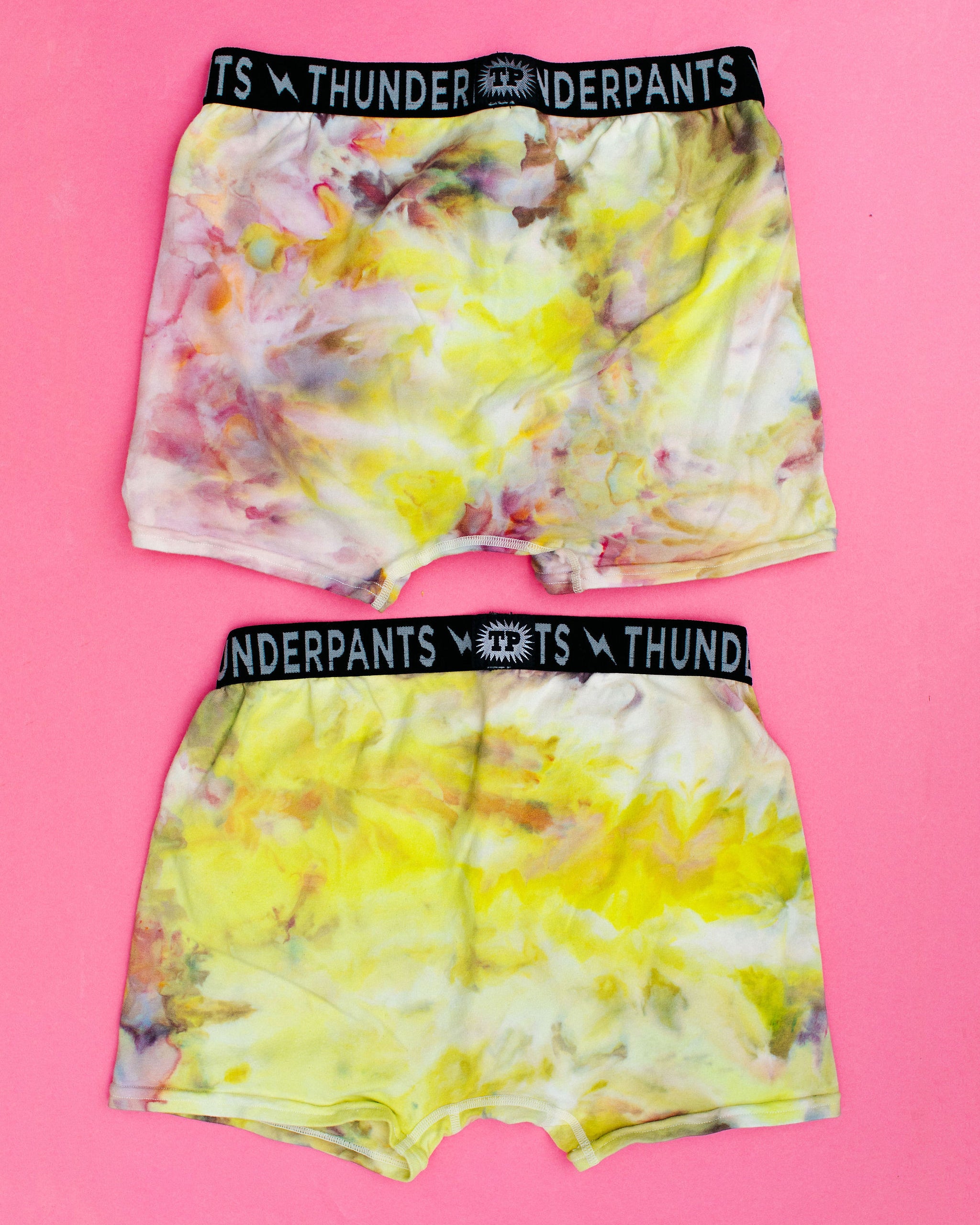 Flat lay of two Thunderpants Boxer Brief style underwear in Citrus Blossom Dye - hand dyed yellow, pink, and purple.