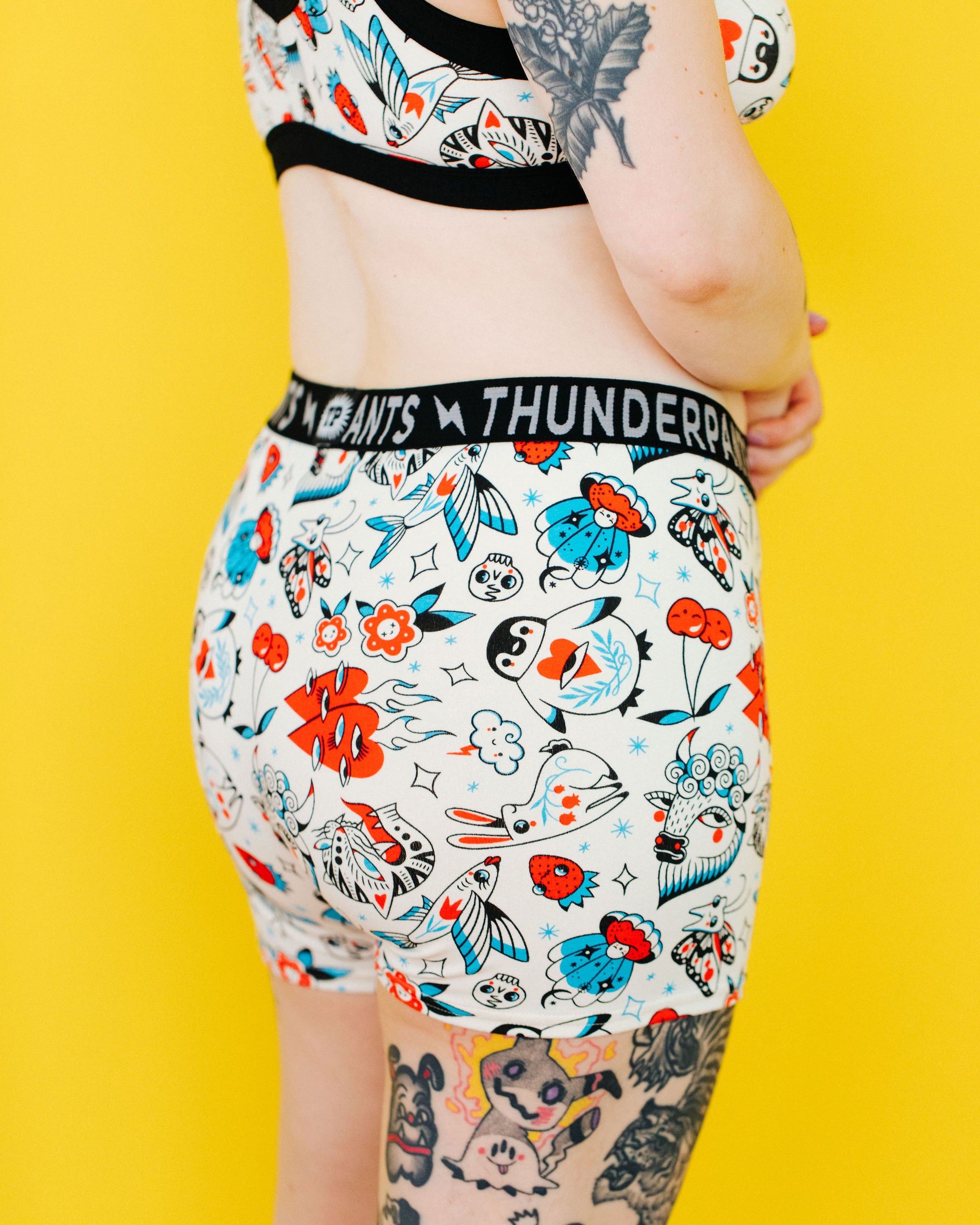 Model wearing Thunderpants Boxer Brief style underwear and Bralette in Inked Up - a tattoo pattern with black, red, and blue. 