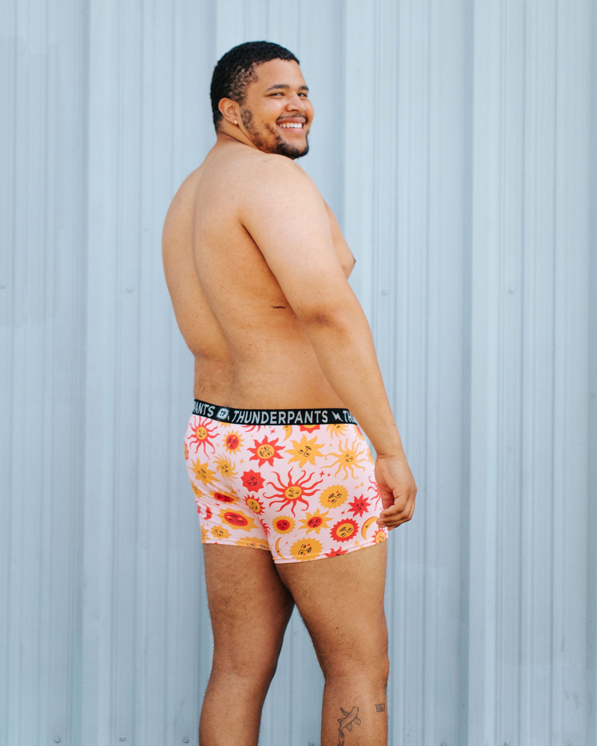 Model wearing Thunderpants Boxer Brief style underwear in Luna y Sol print - pink, yellow, and orange suns and moons.