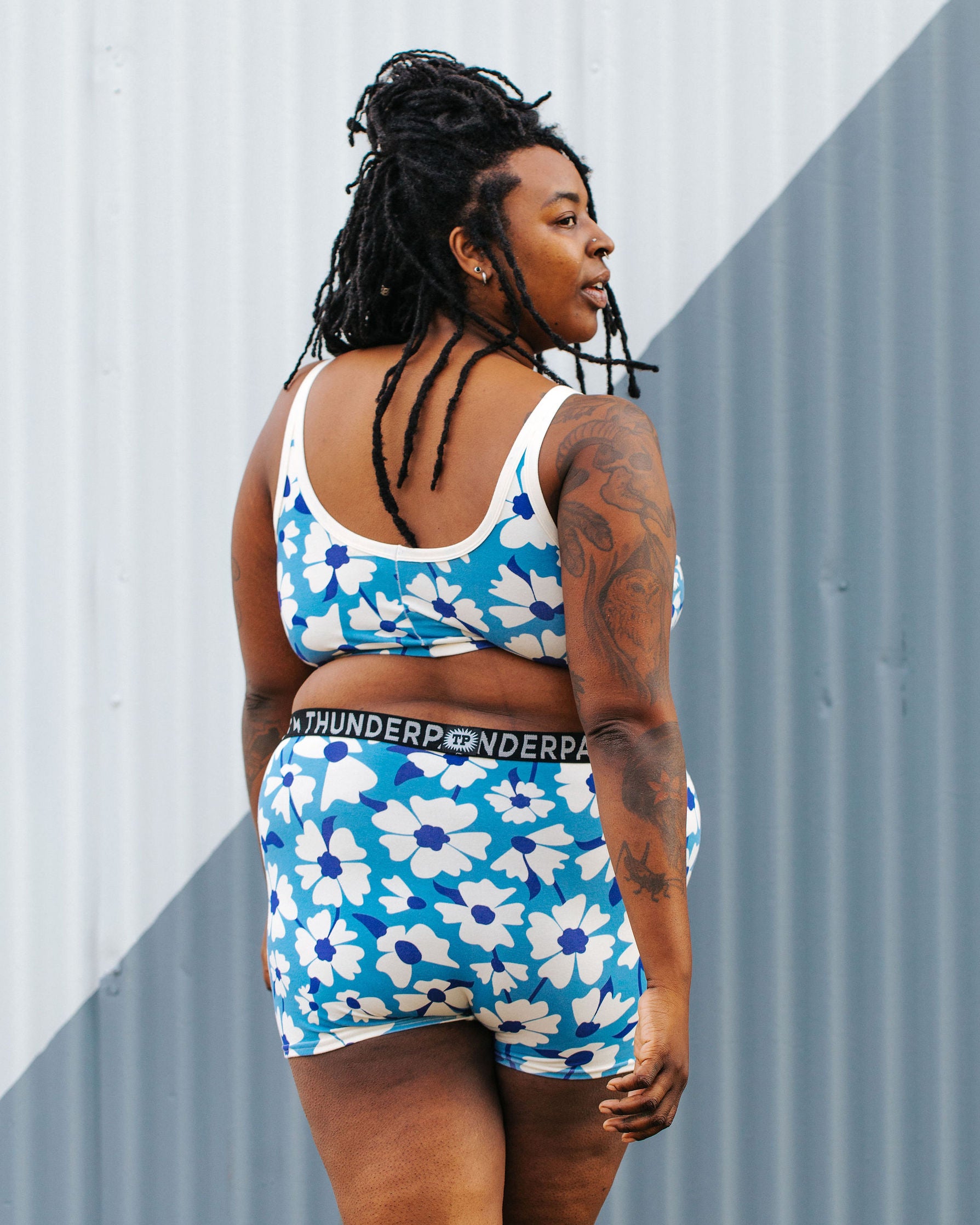 Model wearing Thunderpants Boxer Brief style underwear and Longline Bra in Moody Blooms - white and blue flowers with blue background.