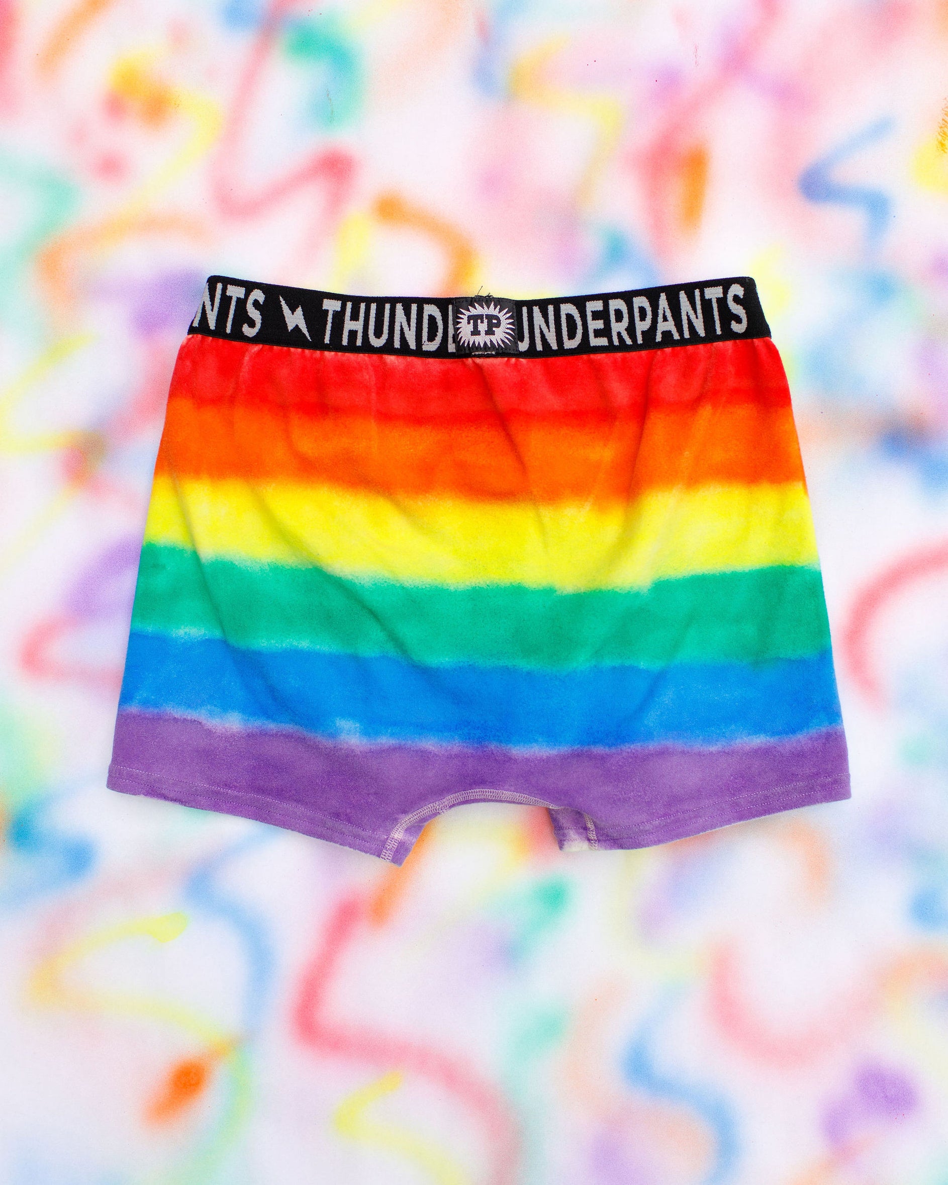 Flat lay of Thunderpants Boxer Brief style underwear in rainbow dye with emerald green binding.
