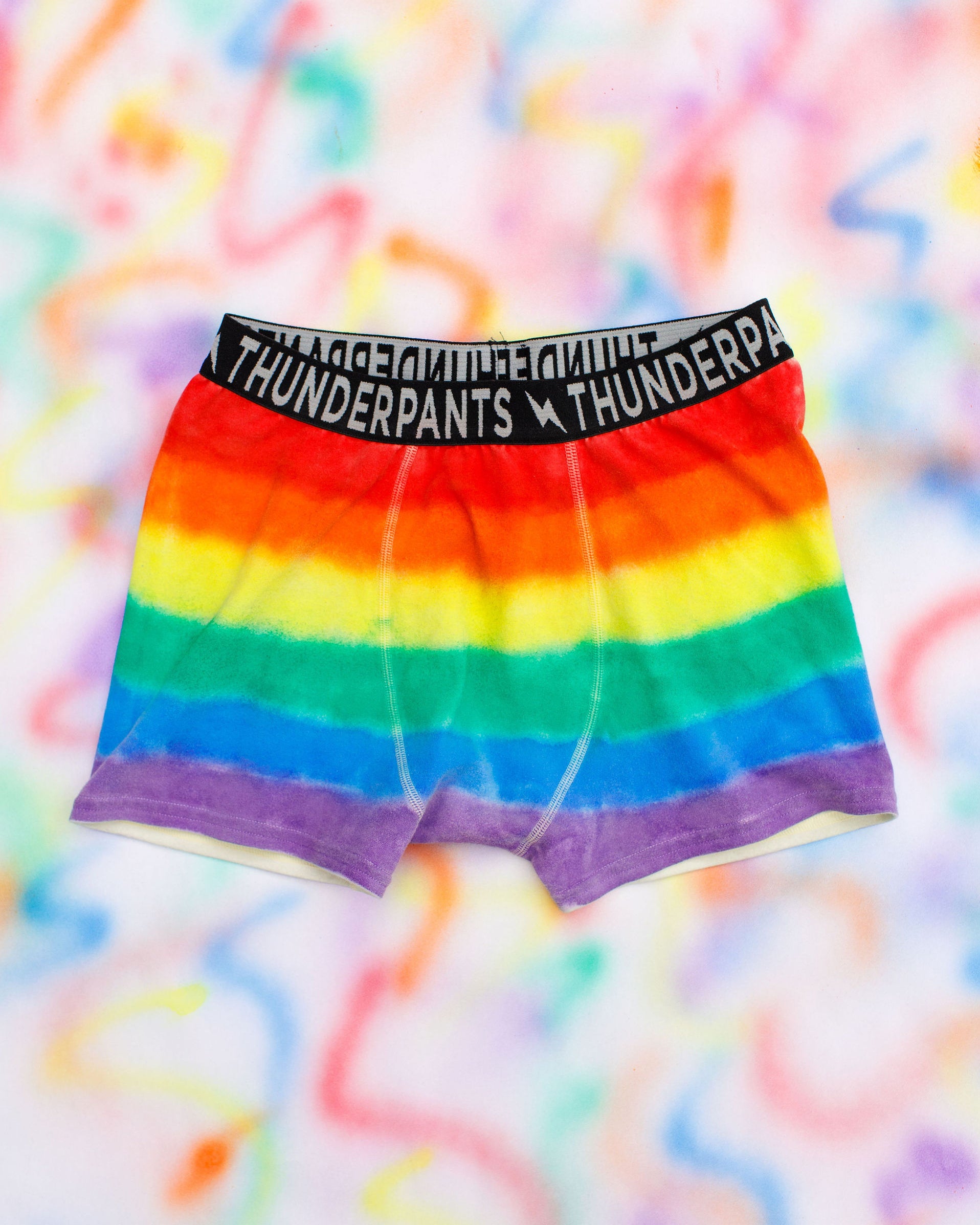 Flat lay of Thunderpants Boxer Brief style underwear in rainbow dye with emerald green binding.