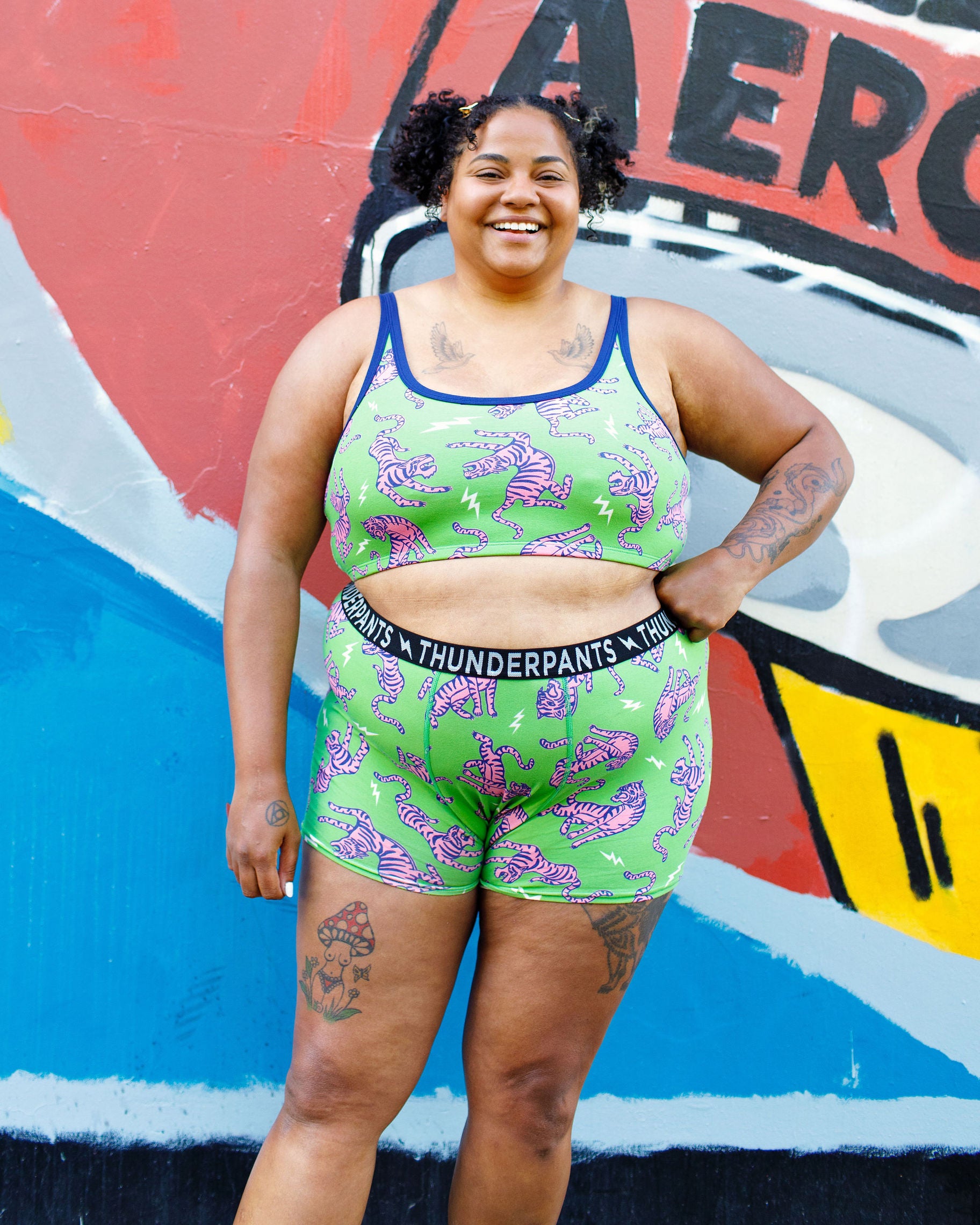 Model wearing Thunderpants organic cotton Boxer Brief and Longline Bra in Electric Tiger - green with pink and blue tigers and white lightning bolts.