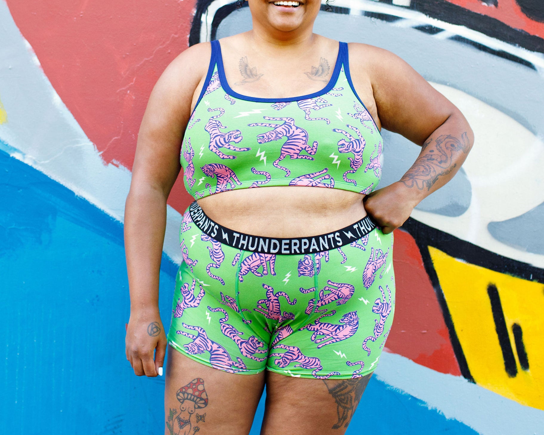 Model wearing Thunderpants organic cotton Boxer Brief and Longline Bra in Electric Tiger - green with pink and blue tigers and white lightning bolts.