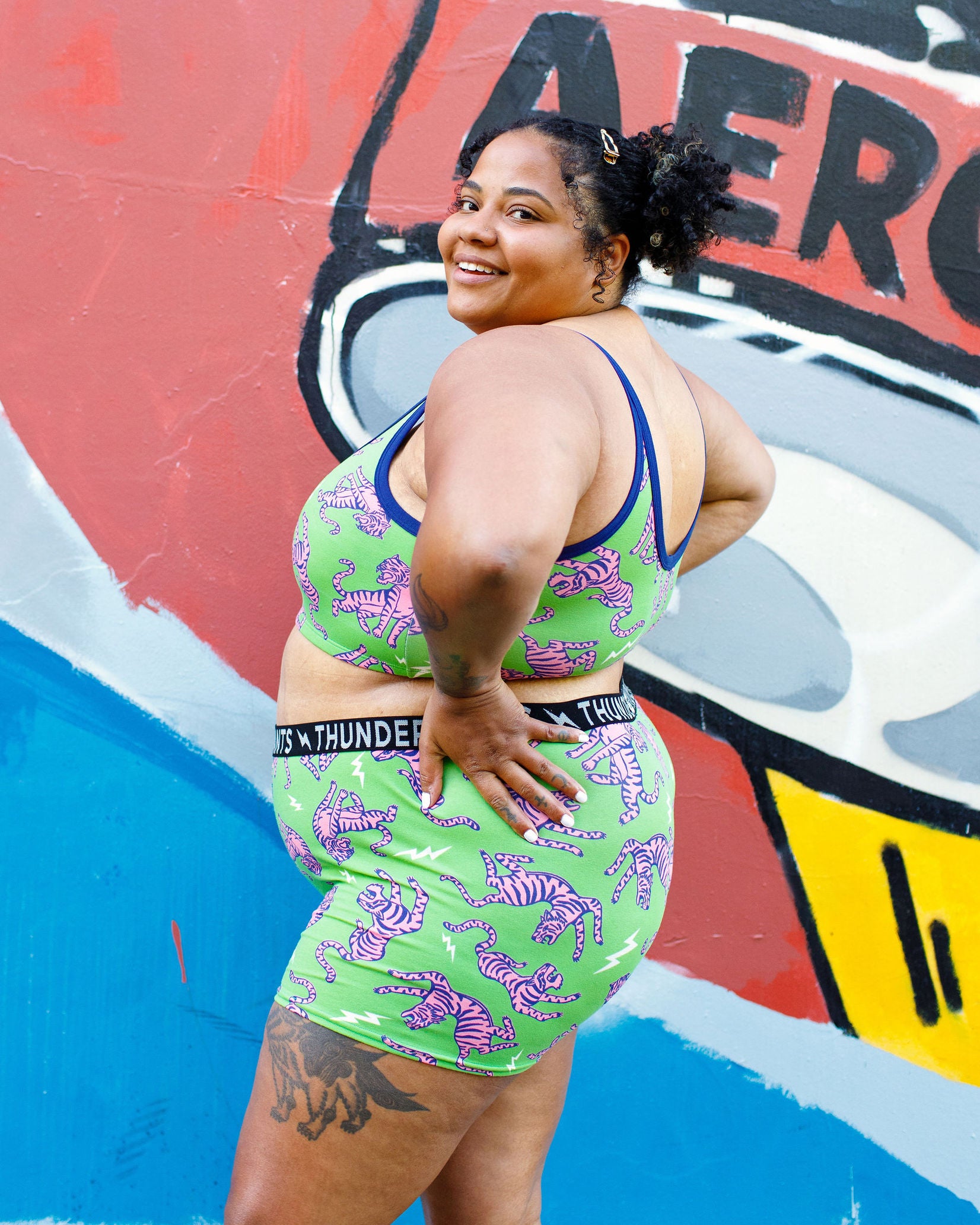 Model wearing Thunderpants organic cotton Boxer Brief and Longline Bra in Electric Tiger - green with pink and blue tigers and white lightning bolts.