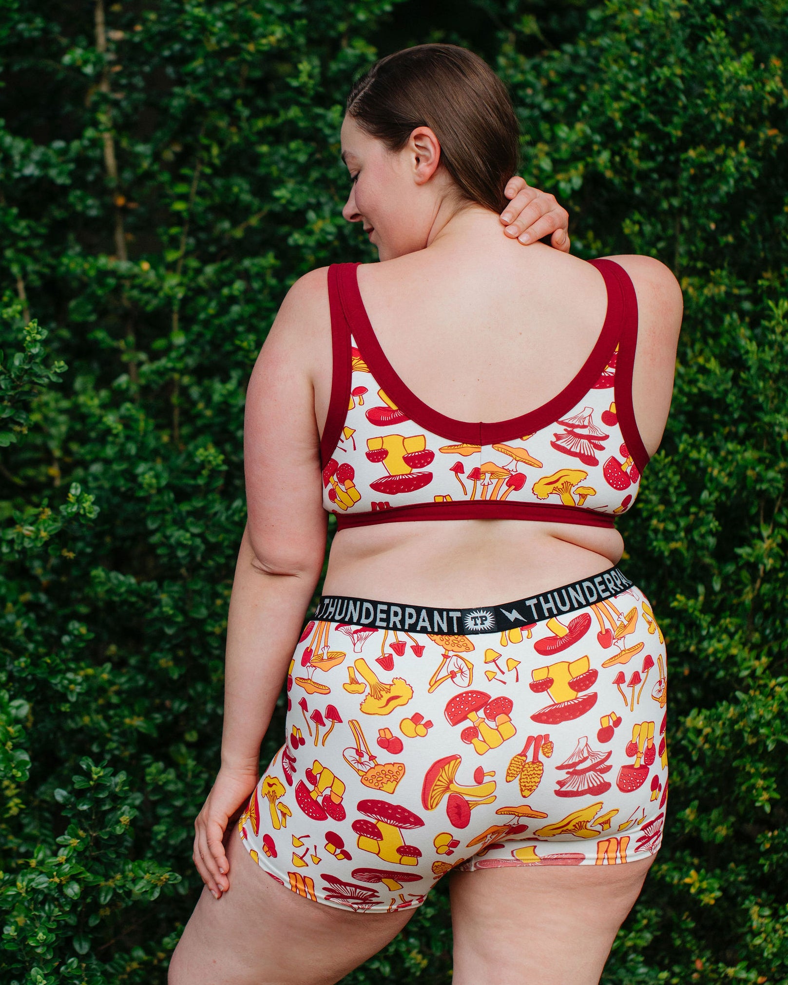 Model wearing Thunderpants Boxer Brief style underwear  and Bralette in Whadda Fungi - red, yellow, and orange mushroom print.