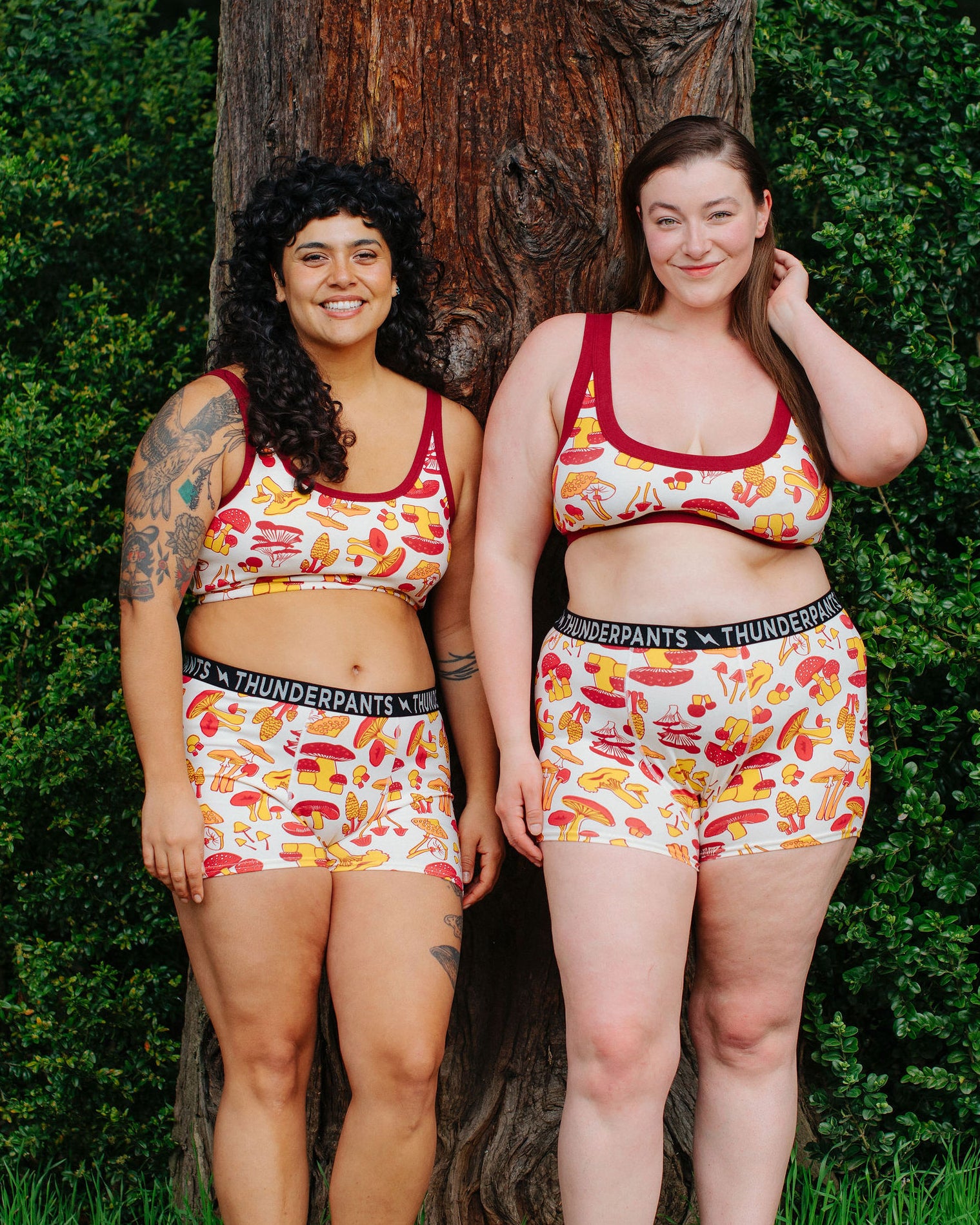 Two models wearing Thunderpants Boxer Brief style underwear  and Bras in Whadda Fungi - red, yellow, and orange mushroom print.