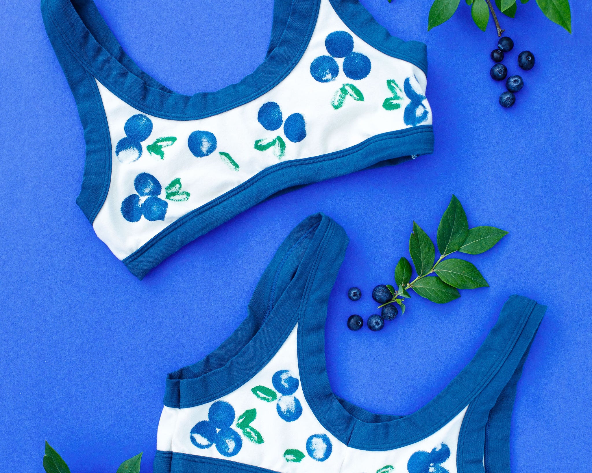 Flat lay of Thunderpants Bralette with a blue and green Blueberry print and blue binding. 
