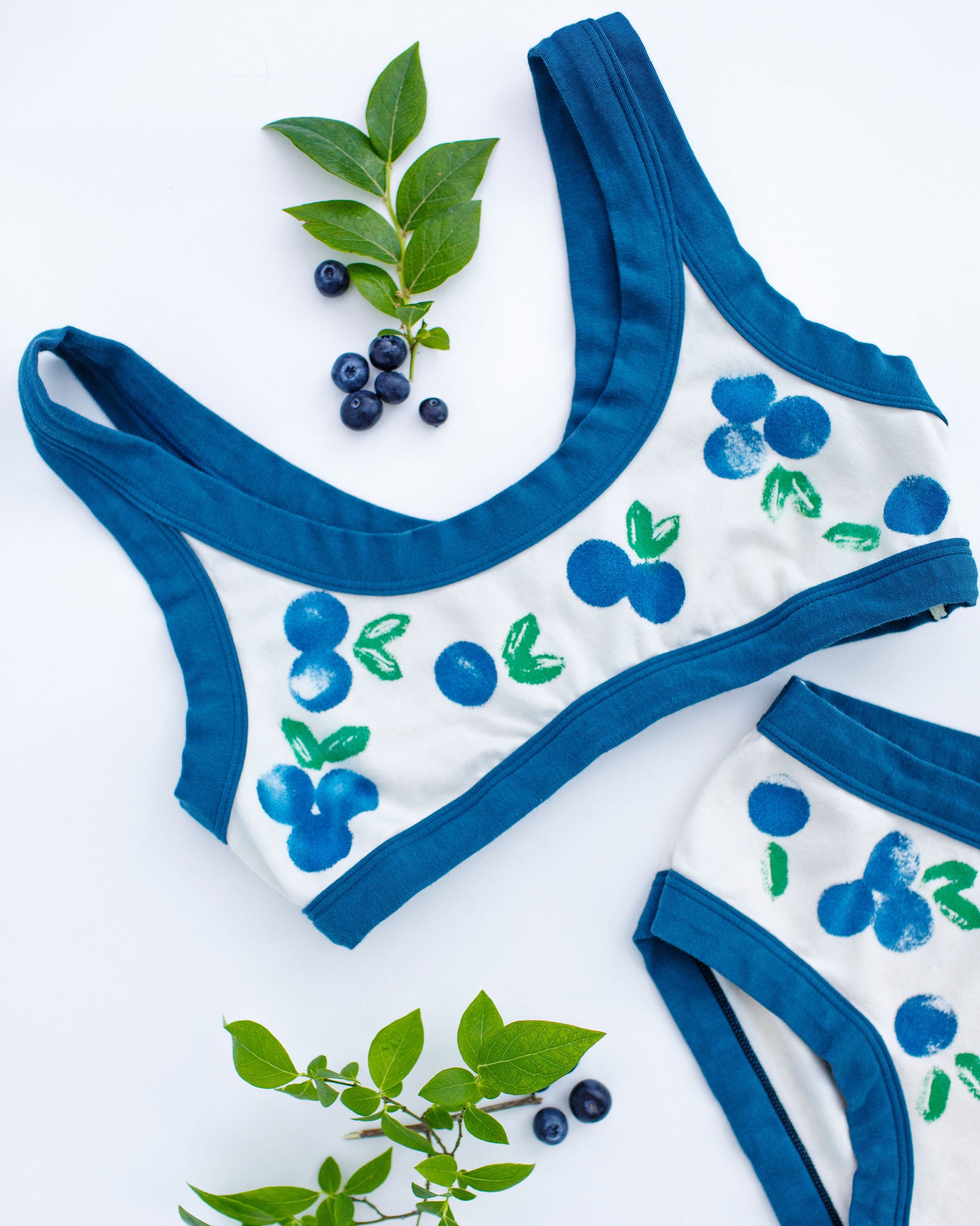 Flat lay of Thunderpants Bralette with a blue and green Blueberry print and blue binding. 