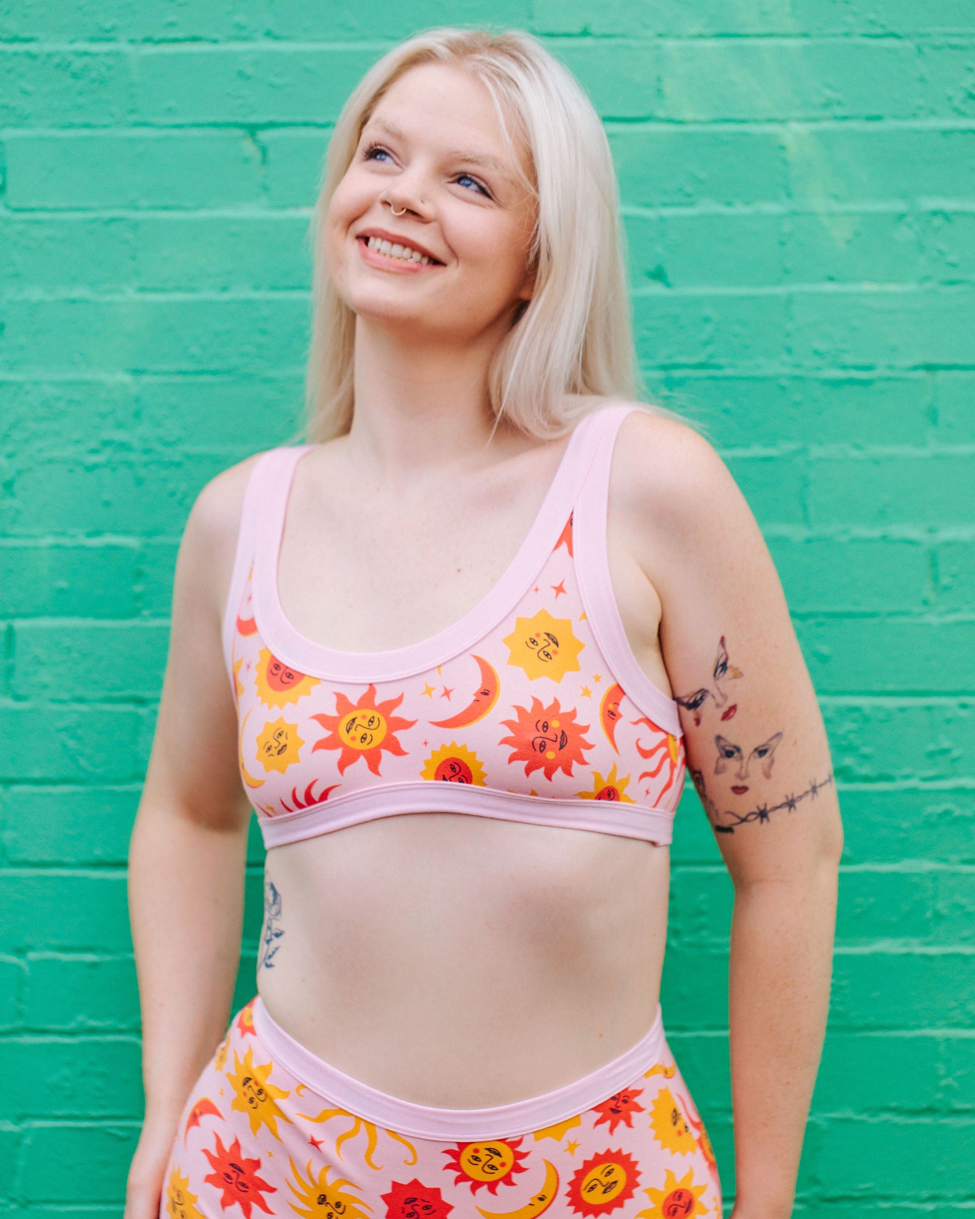 Model wearing Thunderpants Bralette in Luna y Sol print - pink, yellow, and orange suns and moons.