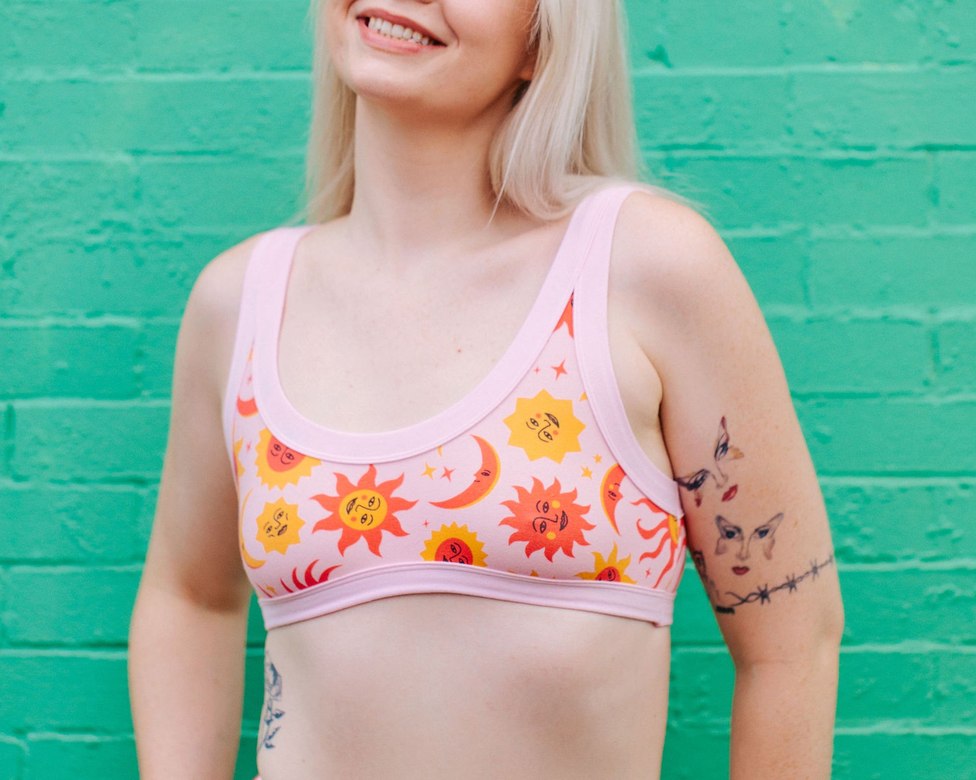 Model wearing Thunderpants Bralette in Luna y Sol print - pink, yellow, and orange suns and moons.