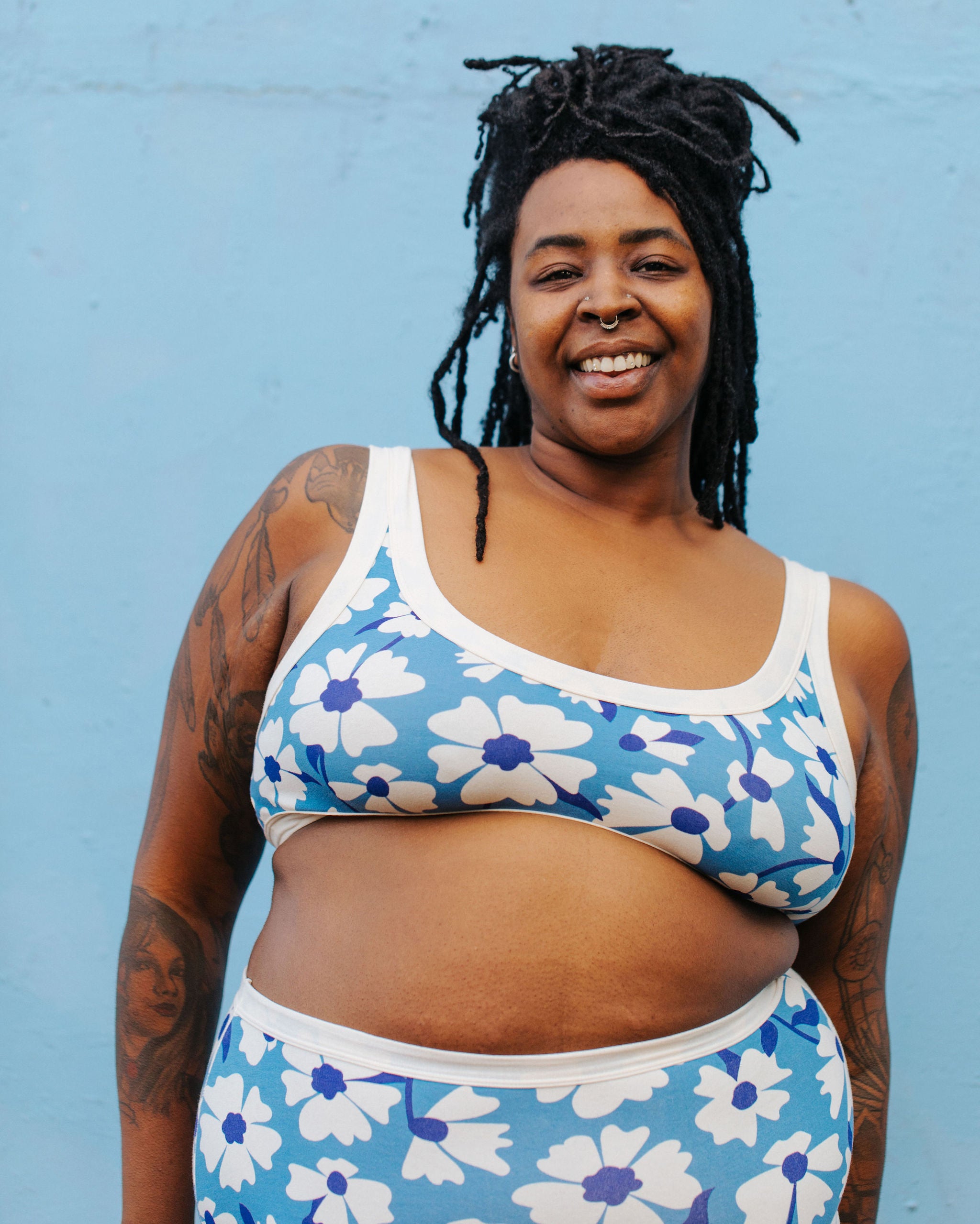 Model wearing Thunderpants Bralette in Moody Blooms - white and blue flowers with blue background.