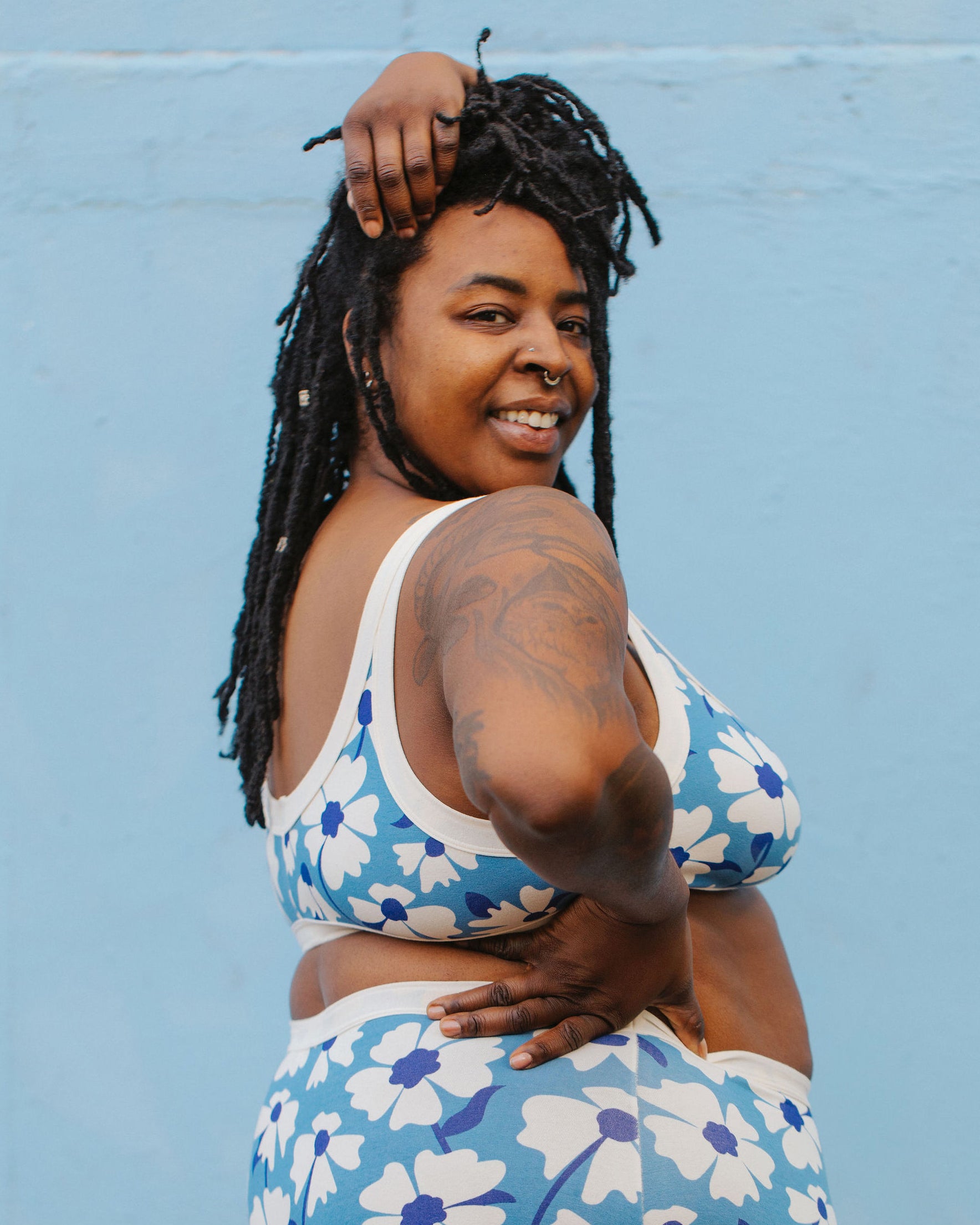 Model wearing Thunderpants Bralette in Moody Blooms - white and blue flowers with blue background.