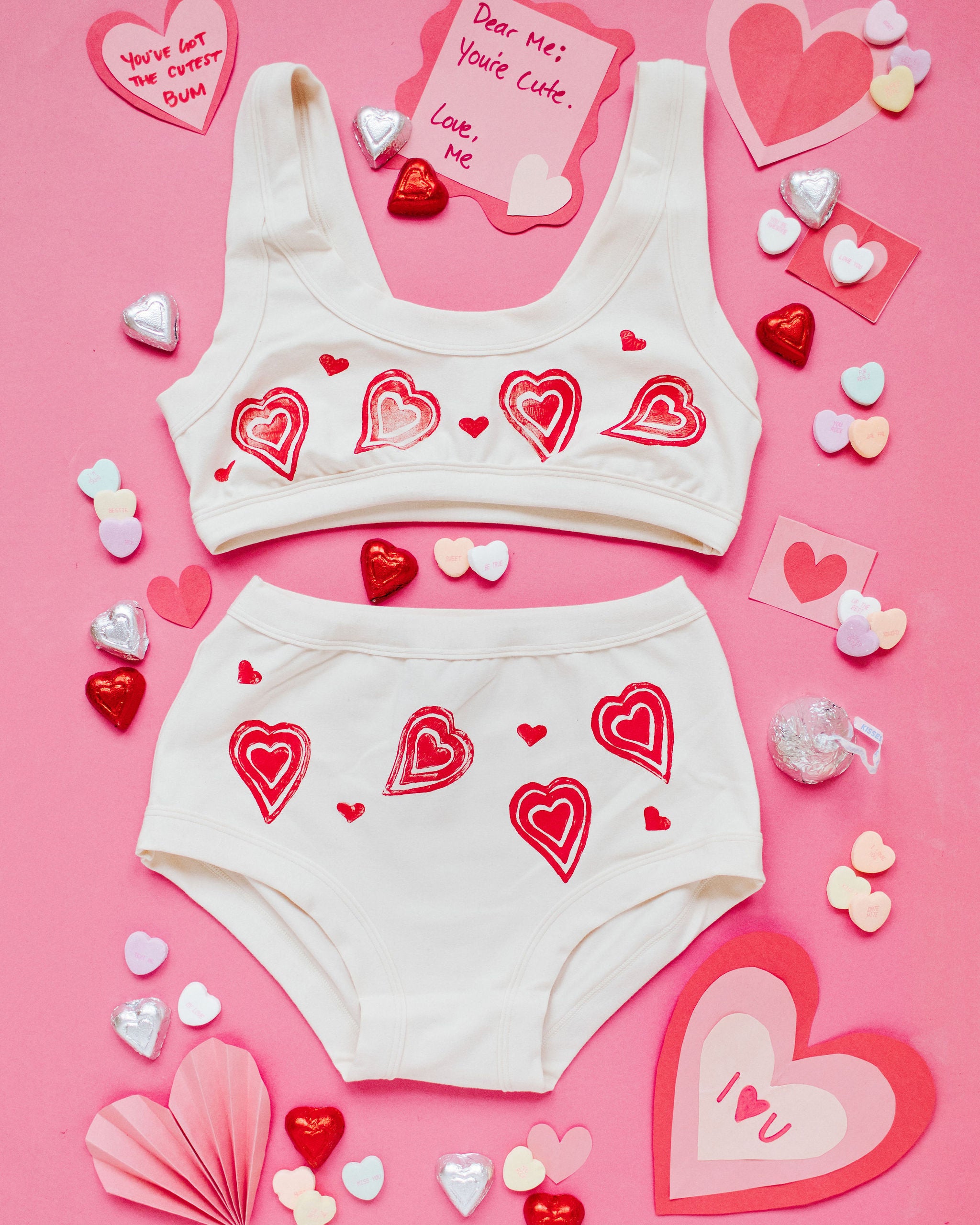 Flat lay of Thunderpants Bralette and Original style underwear with hand printed red hearts on Vanilla.