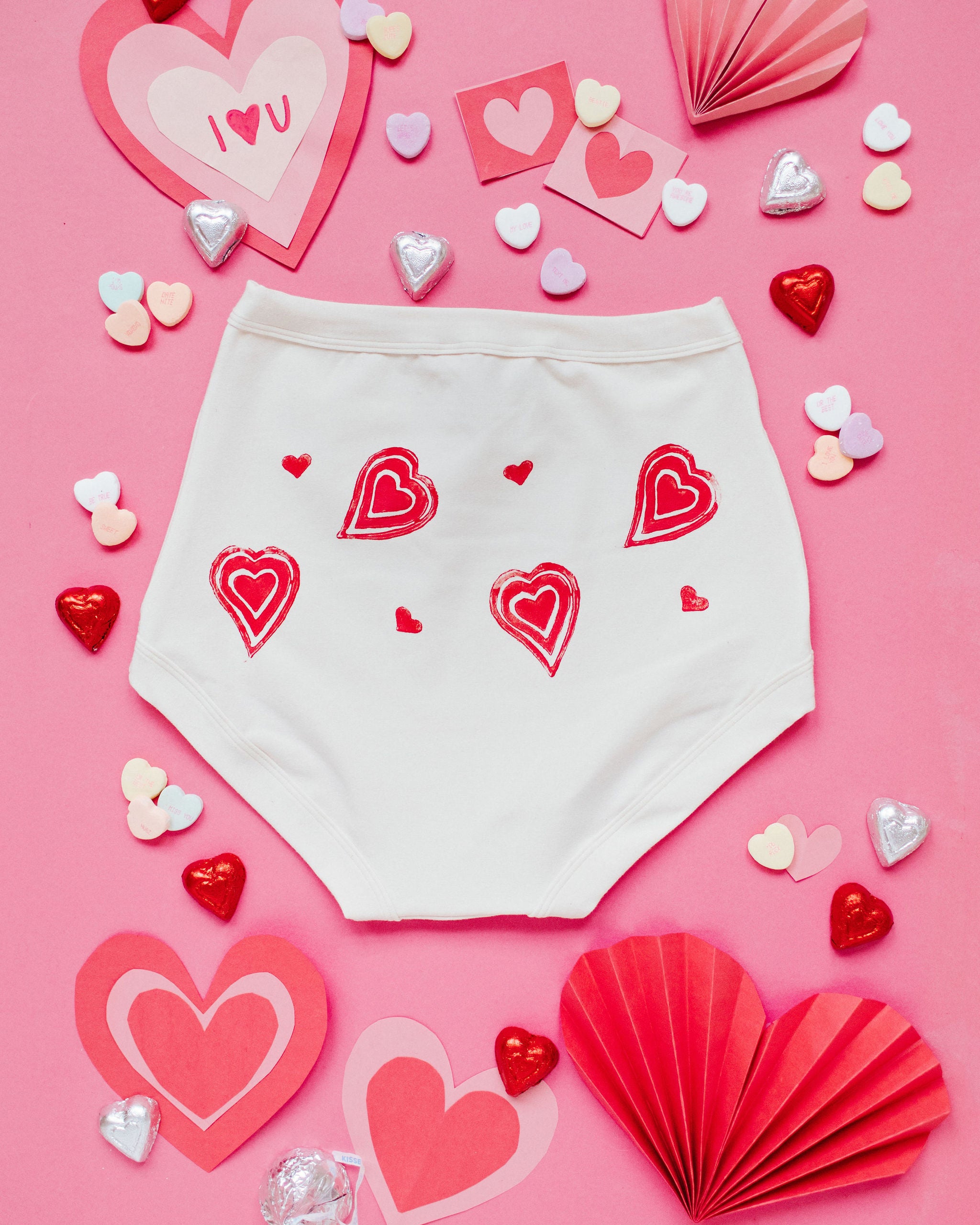 Flat lay of the back of Thunderpants Sky Rise style underwear with hand printed red hearts on Vanilla.