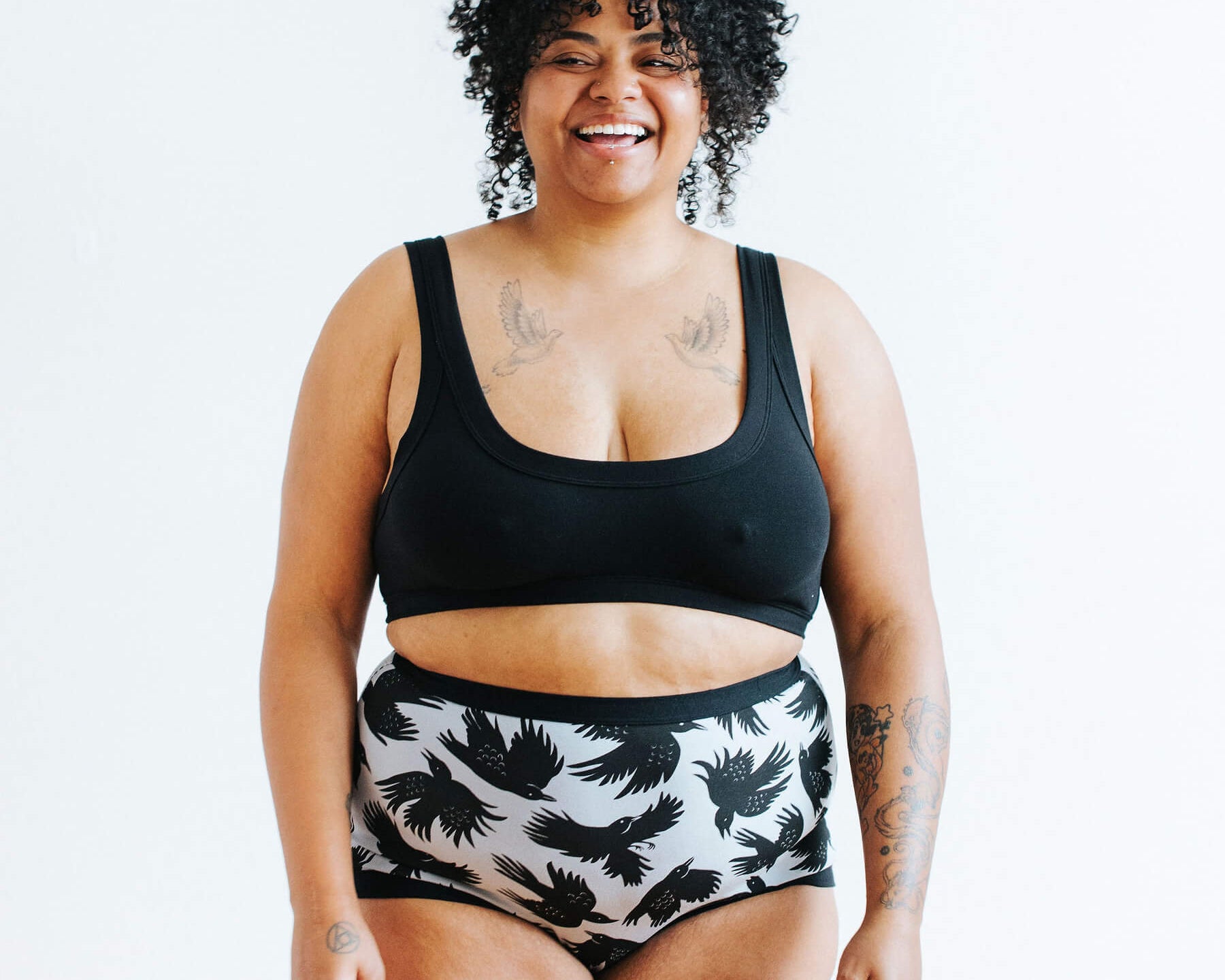 Model wearing Thunderpants Sky Rise style underwear in So it Crows - black crows in grey - and Plain Black Bralette.