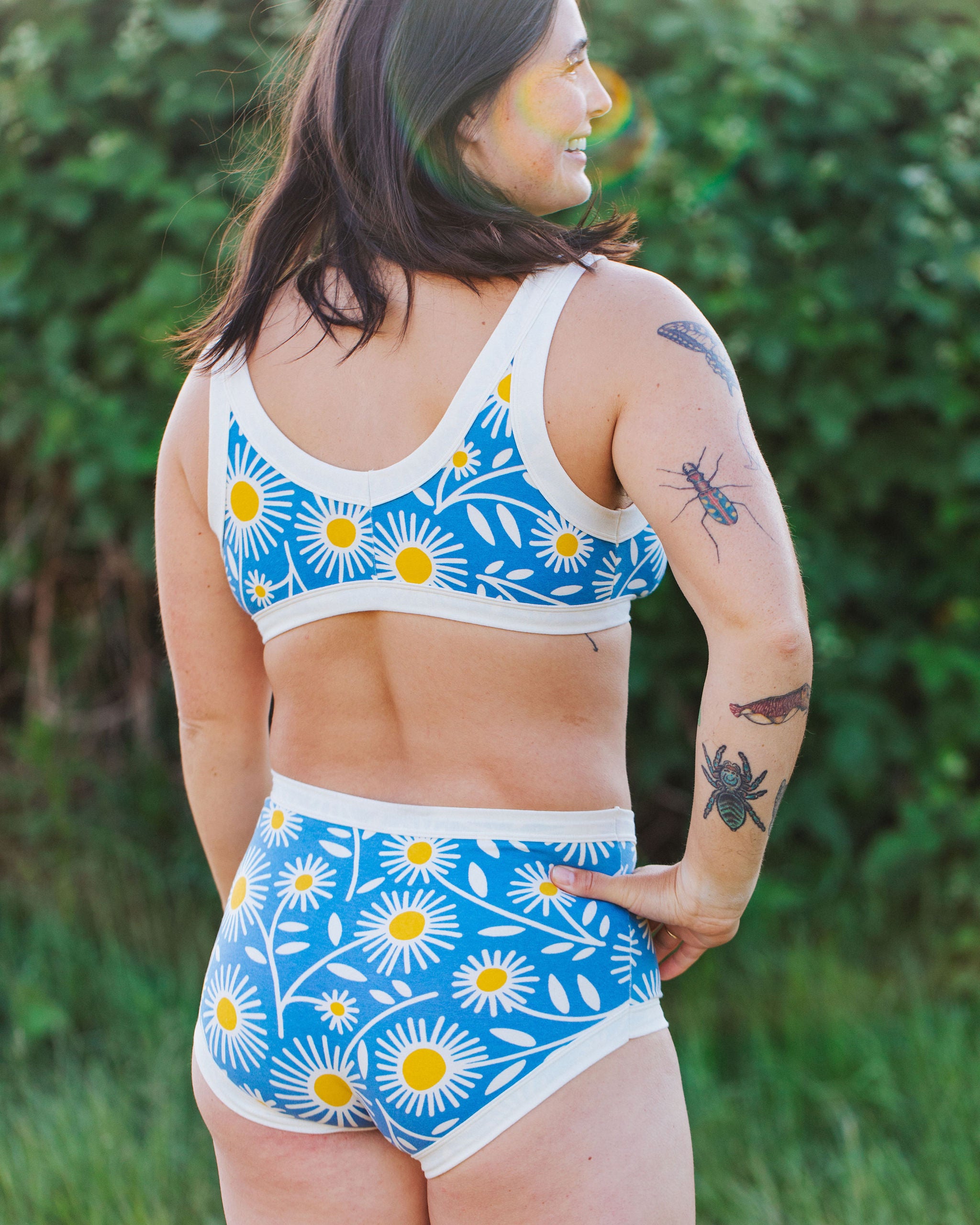 Close up of model wearing Thunderpants Bralette and Original style underwear in Daisy Days print: blue with white and yellow daisies.