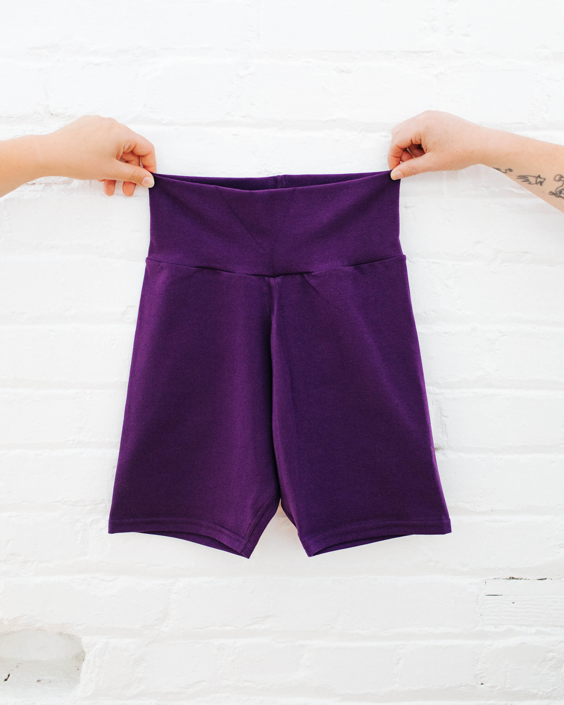 Hands holding up Thunderpants Bike Shorts in Amethyst color.