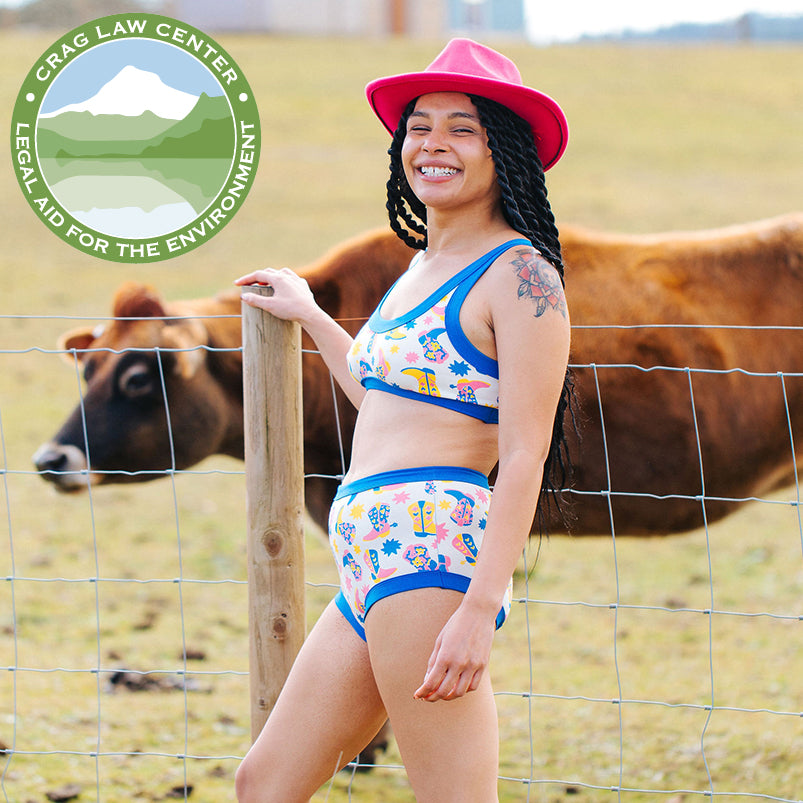 A model standing by a cow wearing a Thunderpants USA set in Boot Scootin' print.