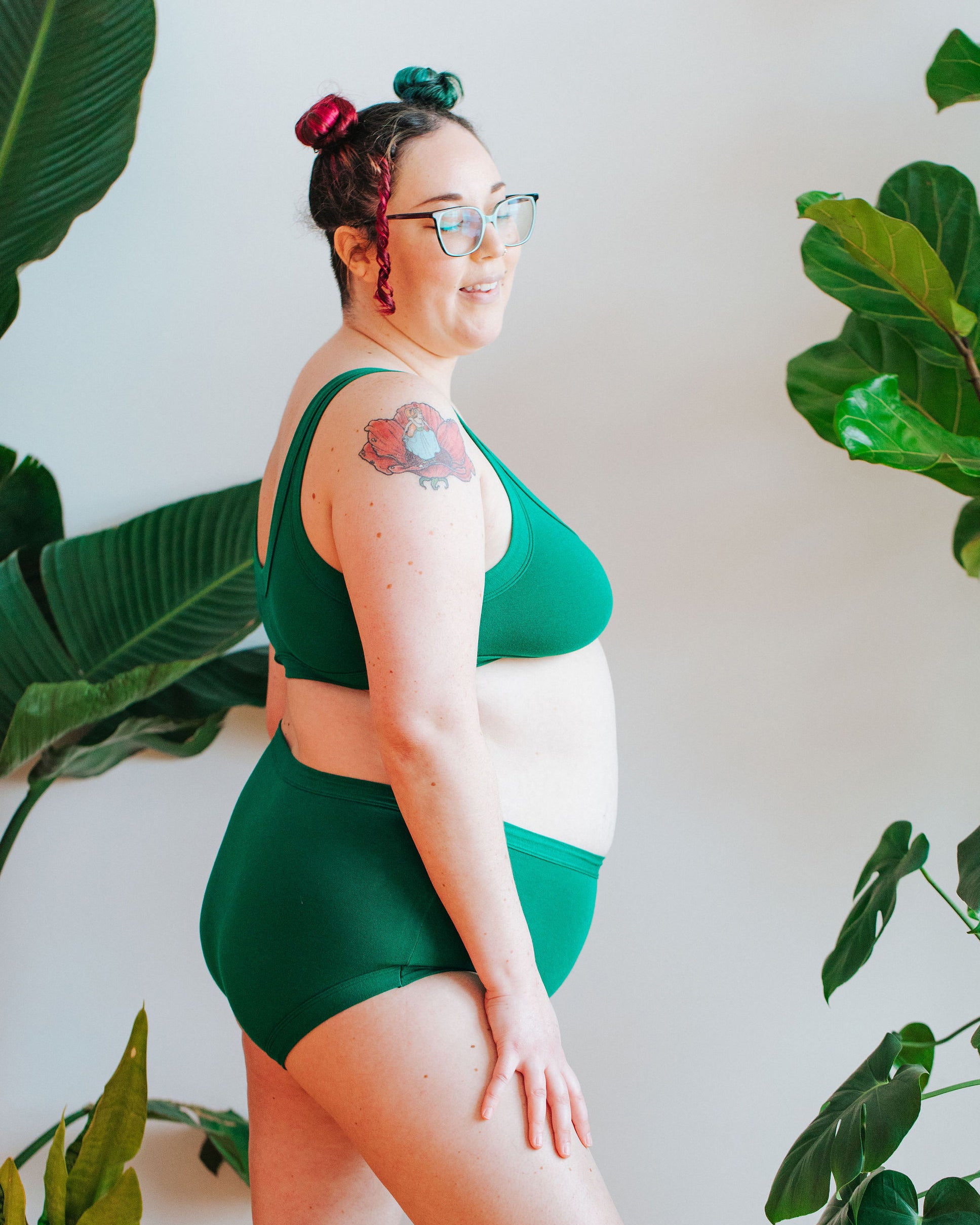 Close up of model in front of a bunch of plants wearing a set of Bralette and Original style underwear in Emerald Green.