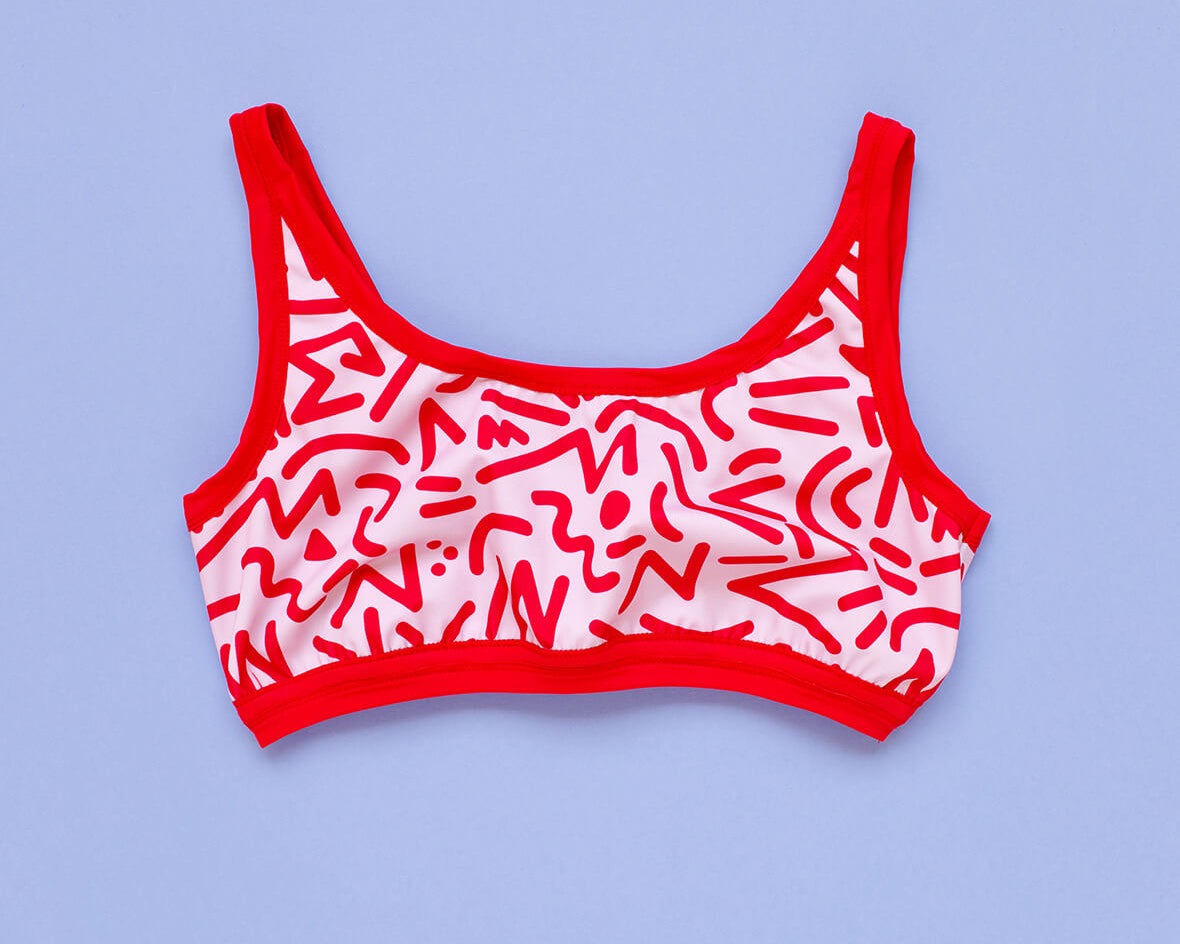 Flat lay of Thunderpants Swim Top in Energy Vibes print: light pink with dark pink designs.