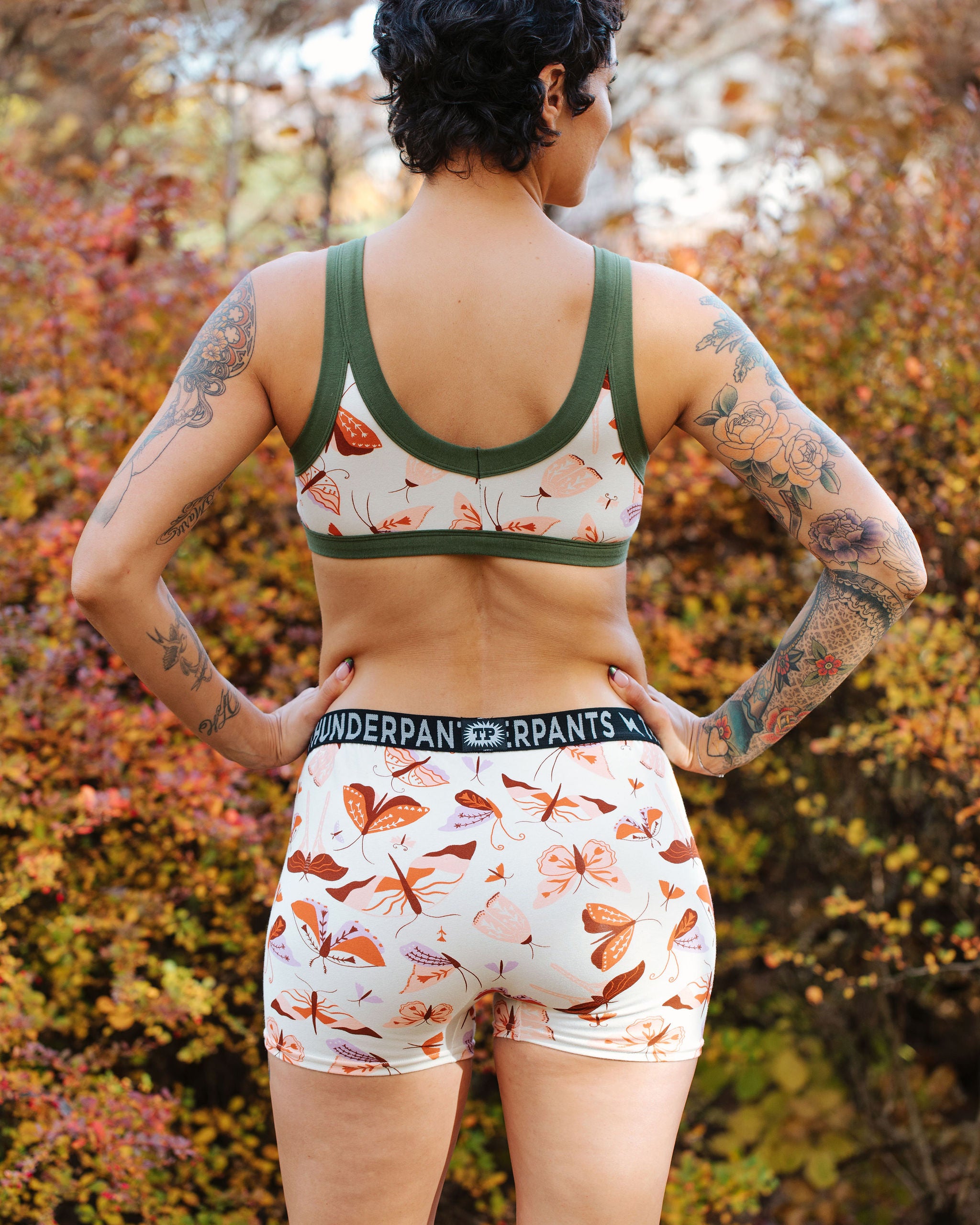 A model wearing Thunderpants Boxer Brief style underwear and Bralette in Field Day: a moth print in red, orange, pink, and purple.