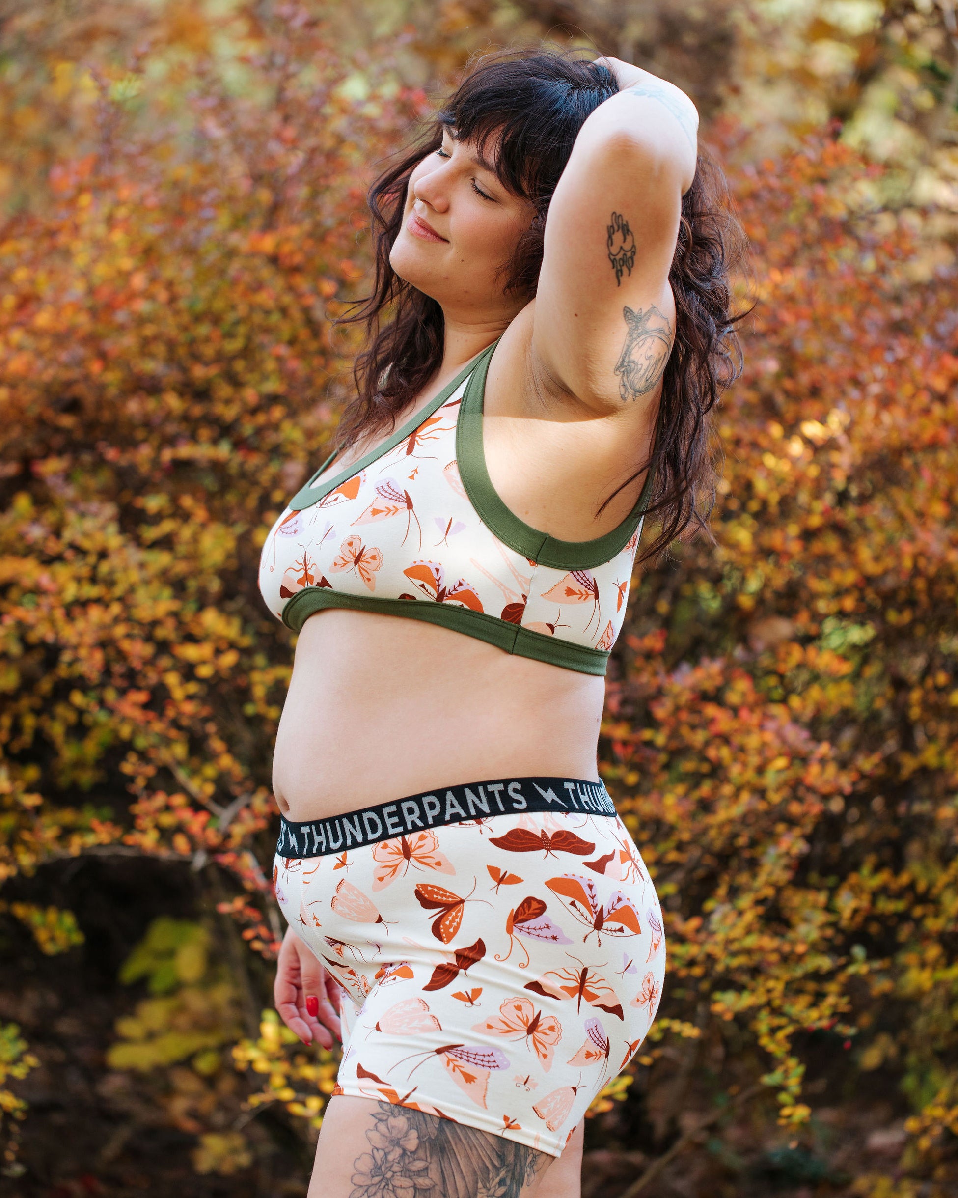 Model wearing Thunderpants Bralette and Boxer Briefs in Field Study: a moth print in red, orange, pink, and purple bound in green.