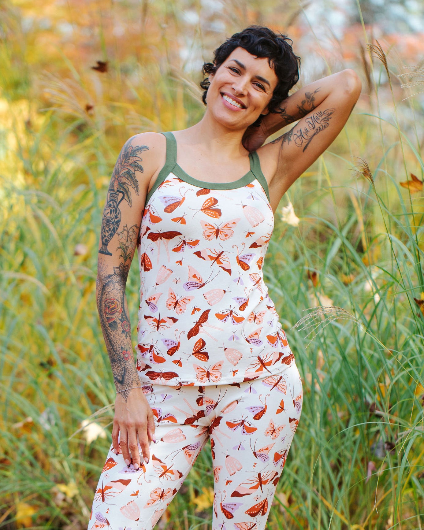 A model wearing Thunderpants Cami and Leggings in Field Study: a moth print in red, orange, pink, and purple bound in green.