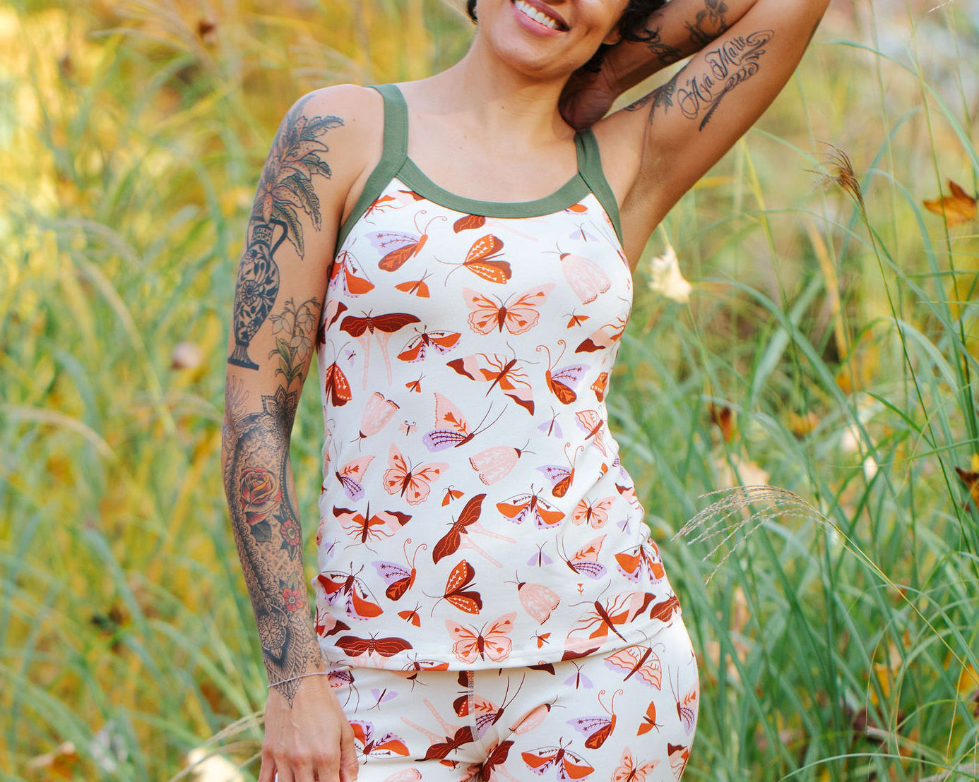 A model wearing Thunderpants Cami and Leggings in Field Study: a moth print in red, orange, pink, and purple bound in green.