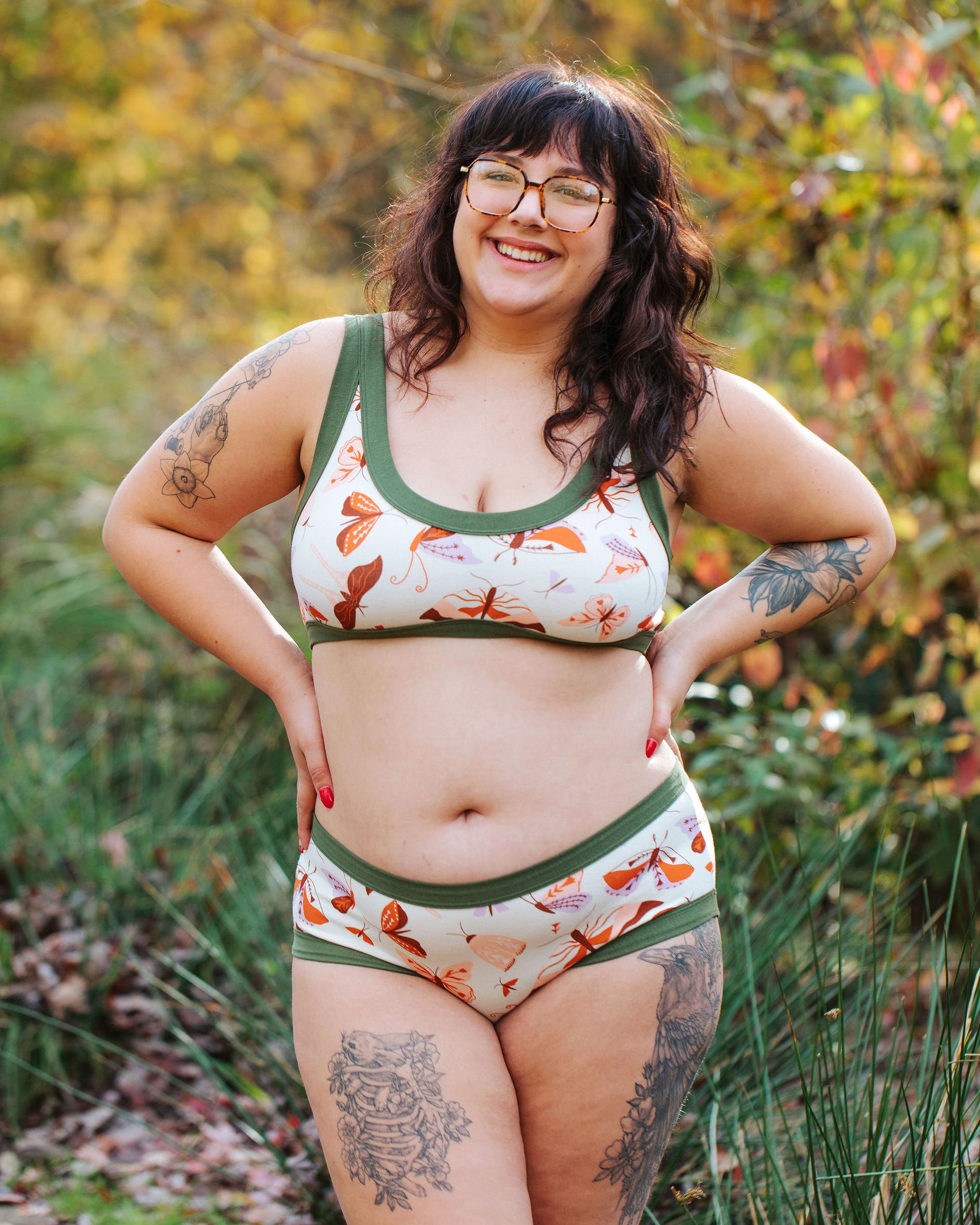 A model wearing Thunderpants Hipster style underwear and Bralette in Field Study: a moth print in red, orange, pink, and purple bound in green.