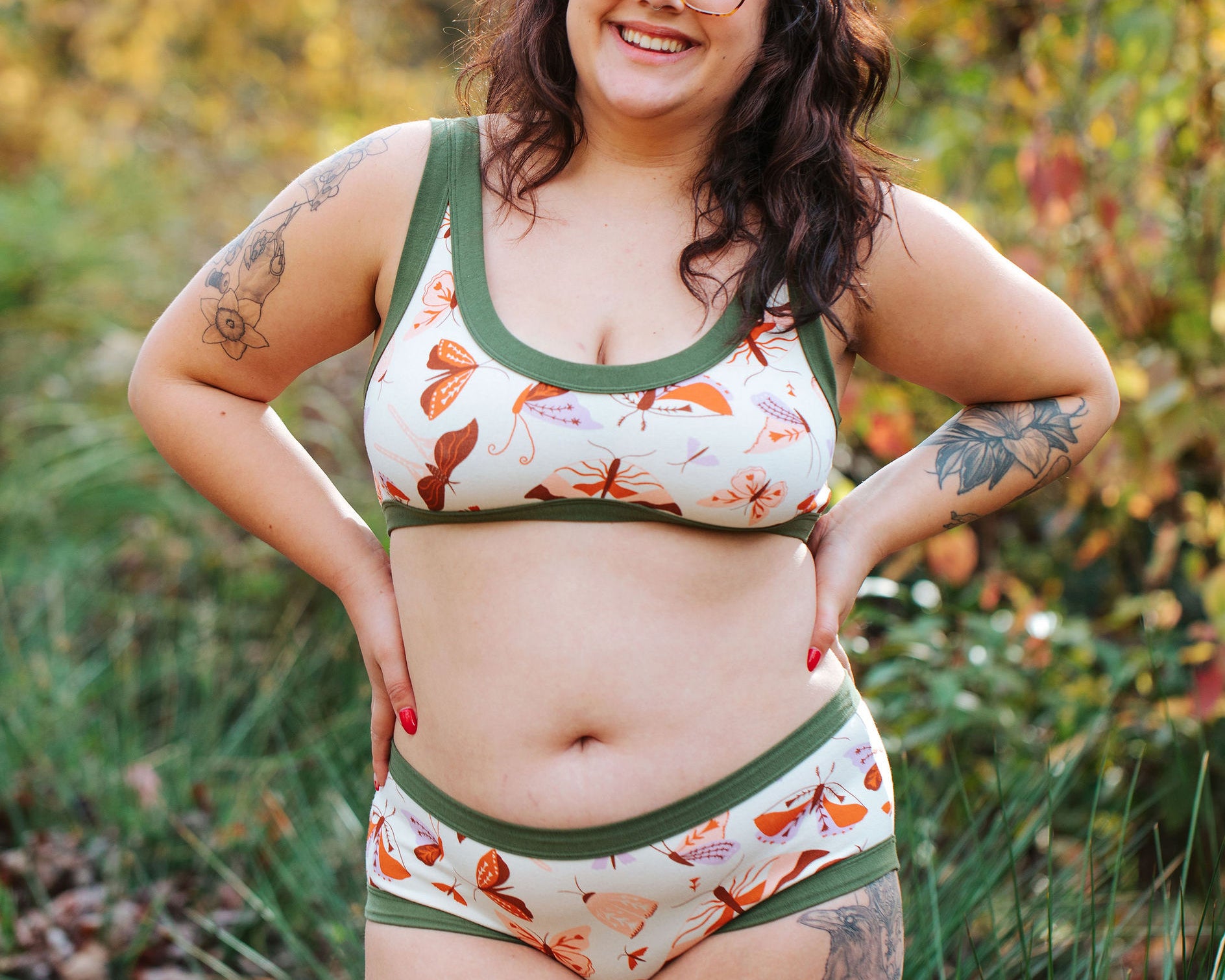 A model wearing Thunderpants Hipster style underwear and Bralette in Field Study: a moth print in red, orange, pink, and purple bound in green.
