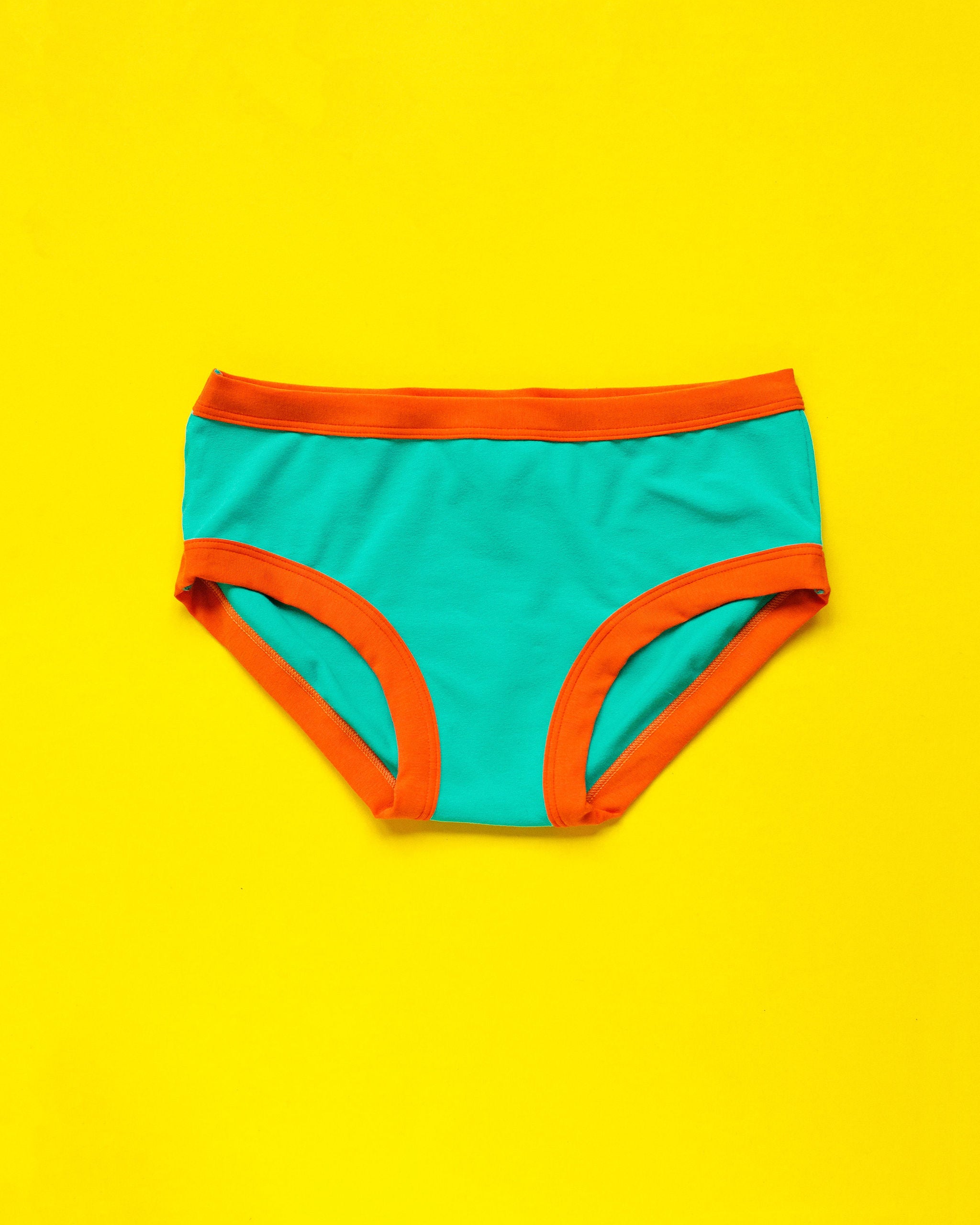 Flat lay of Thunderpants Hipster style underwear in Bird in Paradise - peacock green with orange binding.