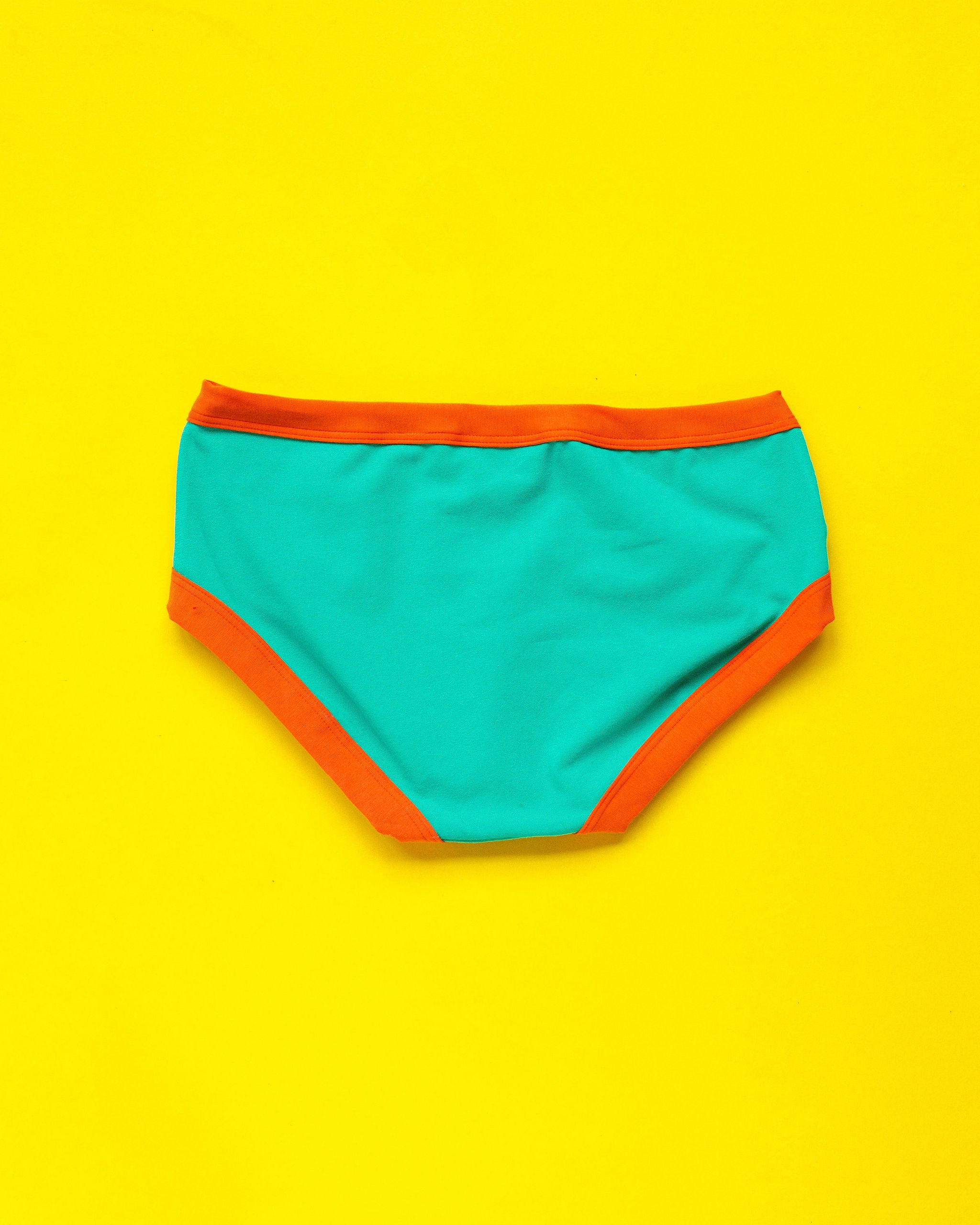 Flat lay of Thunderpants Hipster style underwear in Bird in Paradise - peacock green with orange binding.