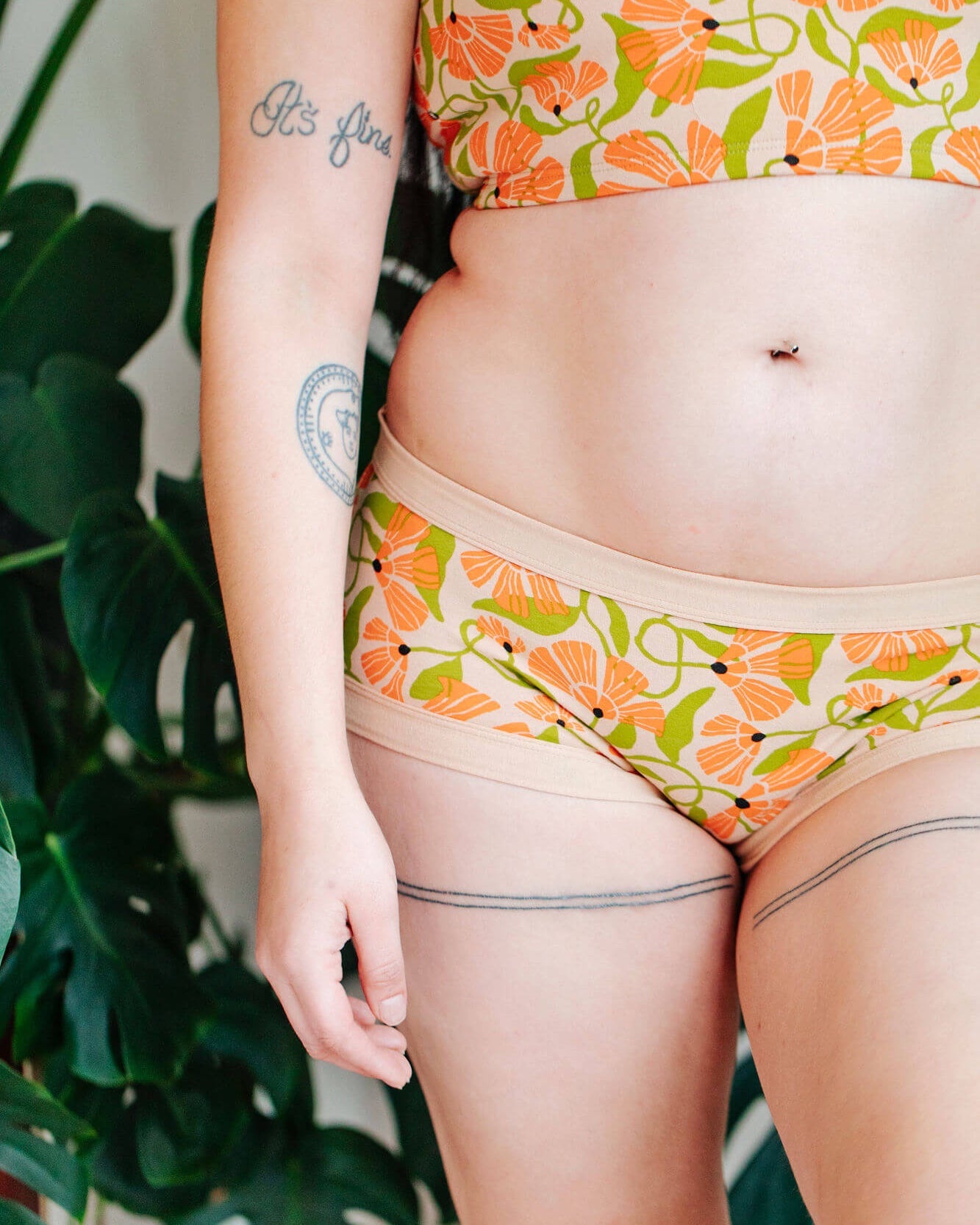 Close up of model wearing a set of Thunderpants Hipster style underwear and Longline Bra in Secret Garden - orange flowers and green leaves.