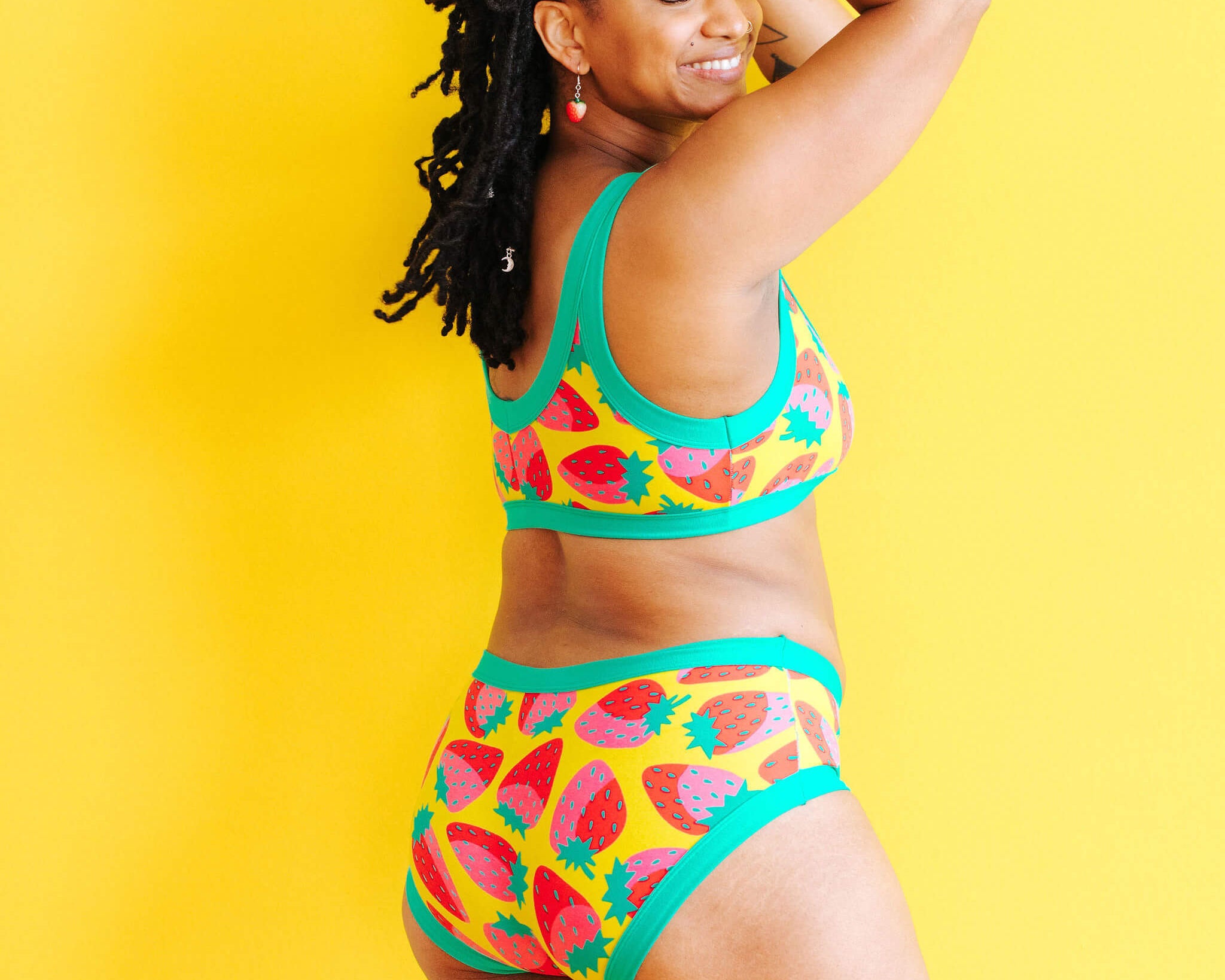 Model wearing Thunderpants Hipster style underwear and Bralette in a Strawberry print - pink, red, and peacock green on chartreuse. 