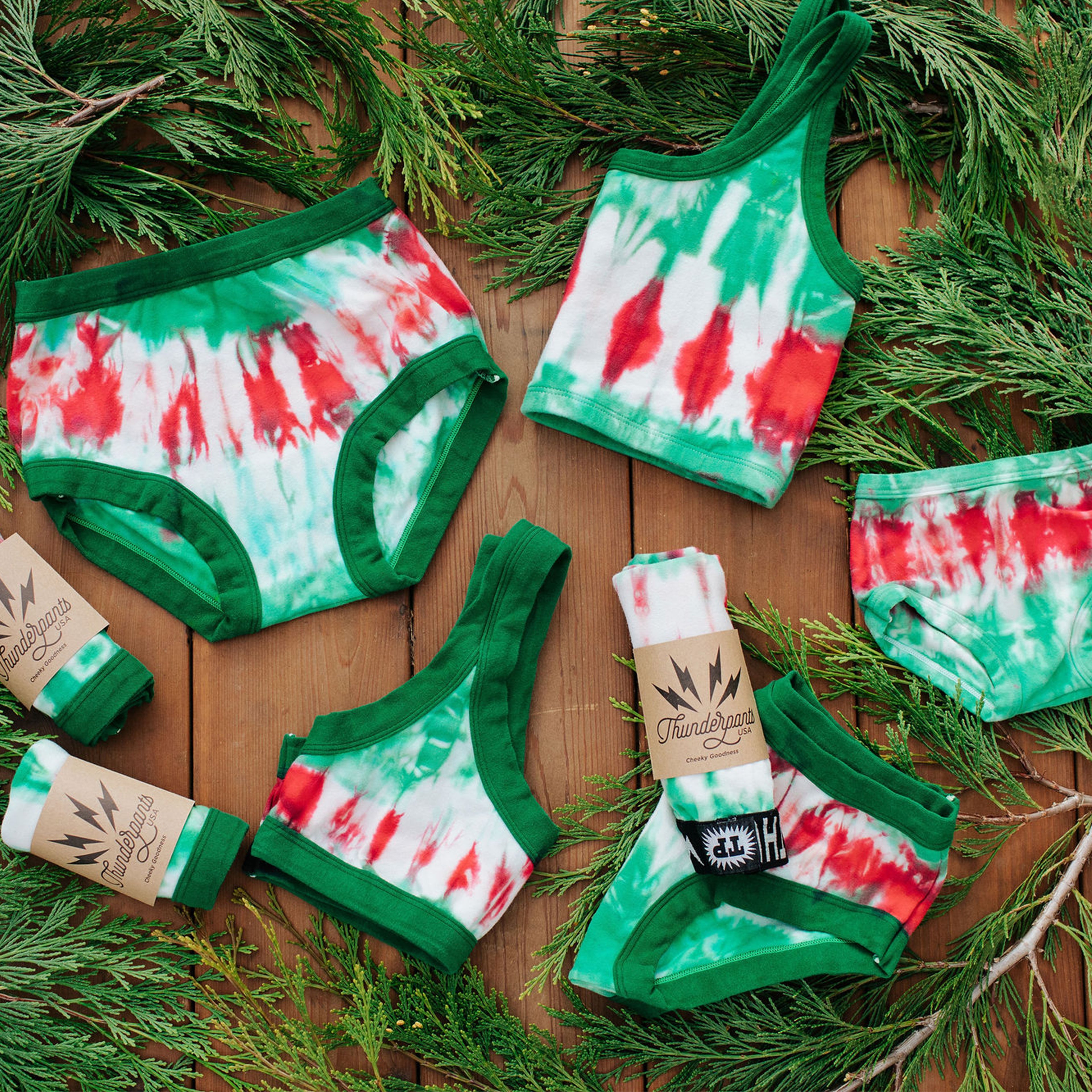 Flat lay of multiple Thunderpants styles in Holiday Tie Dye - red and green dye with green binding.