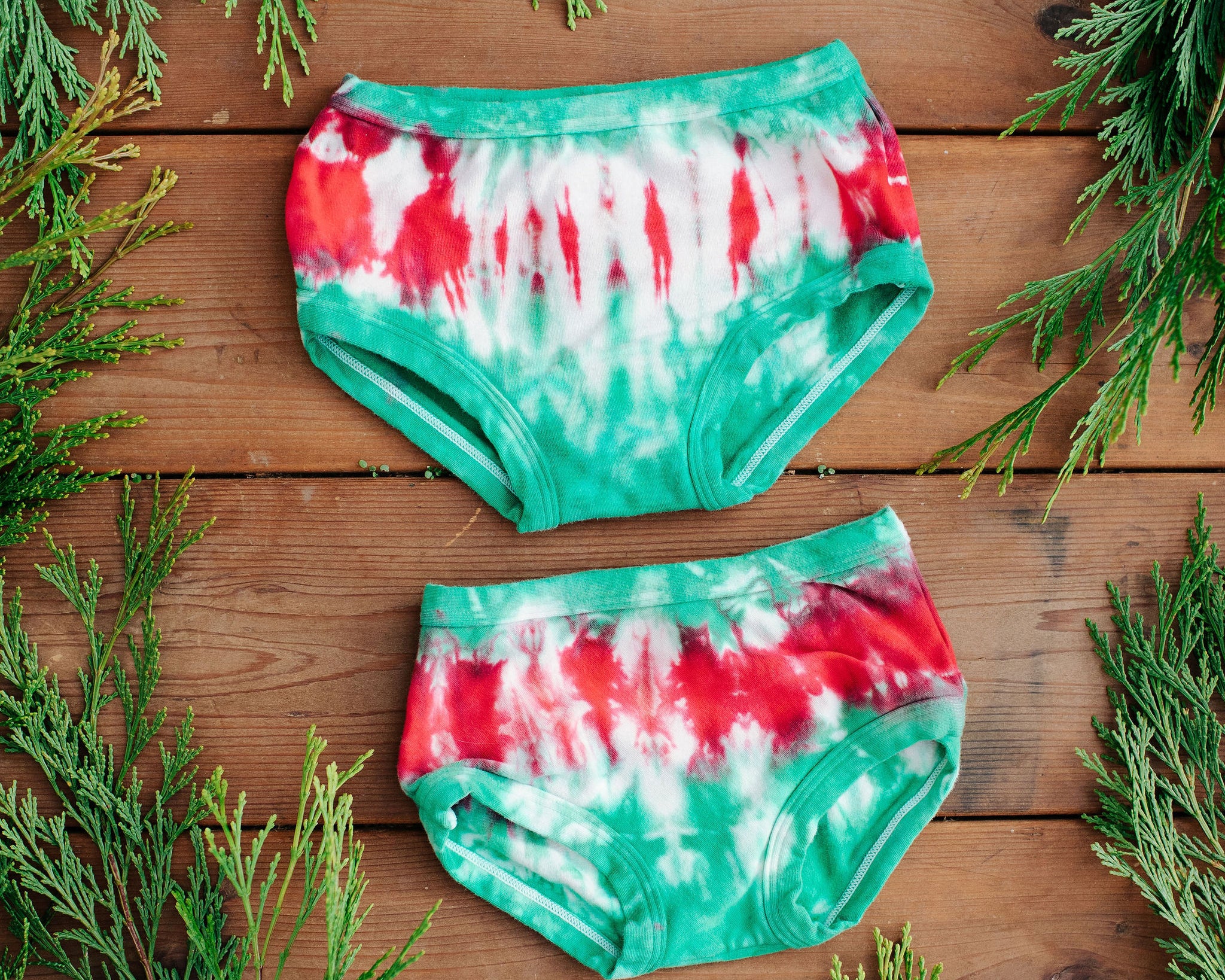 Flay lay of two Thunderpants Kid's style underwear in Holiday Dye - red and green tie dye with green binding. 