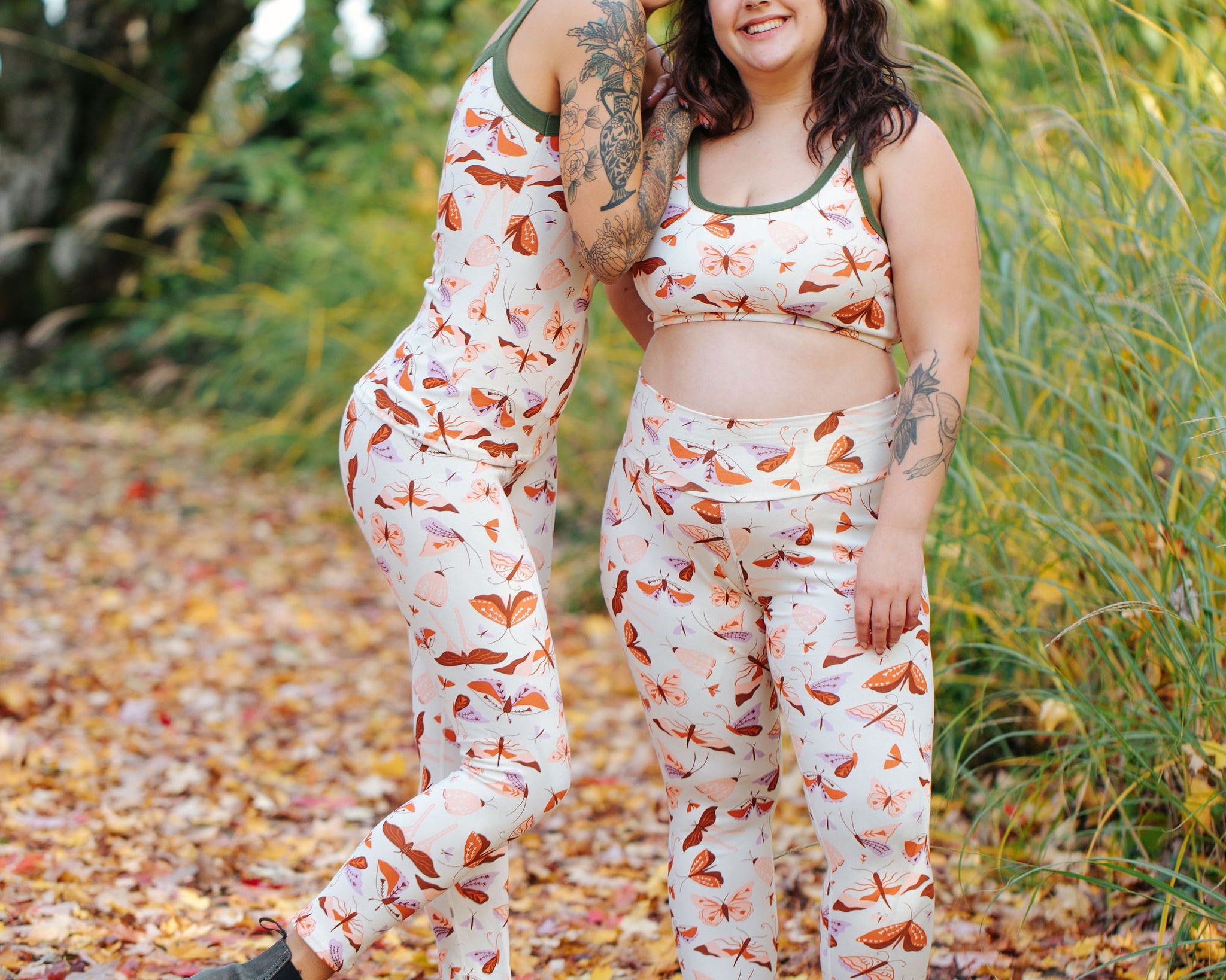 Models wearing Thunderpants Ankle Length Leggings in Field Study: a moth print in red, orange, pink, and purple bound in green.