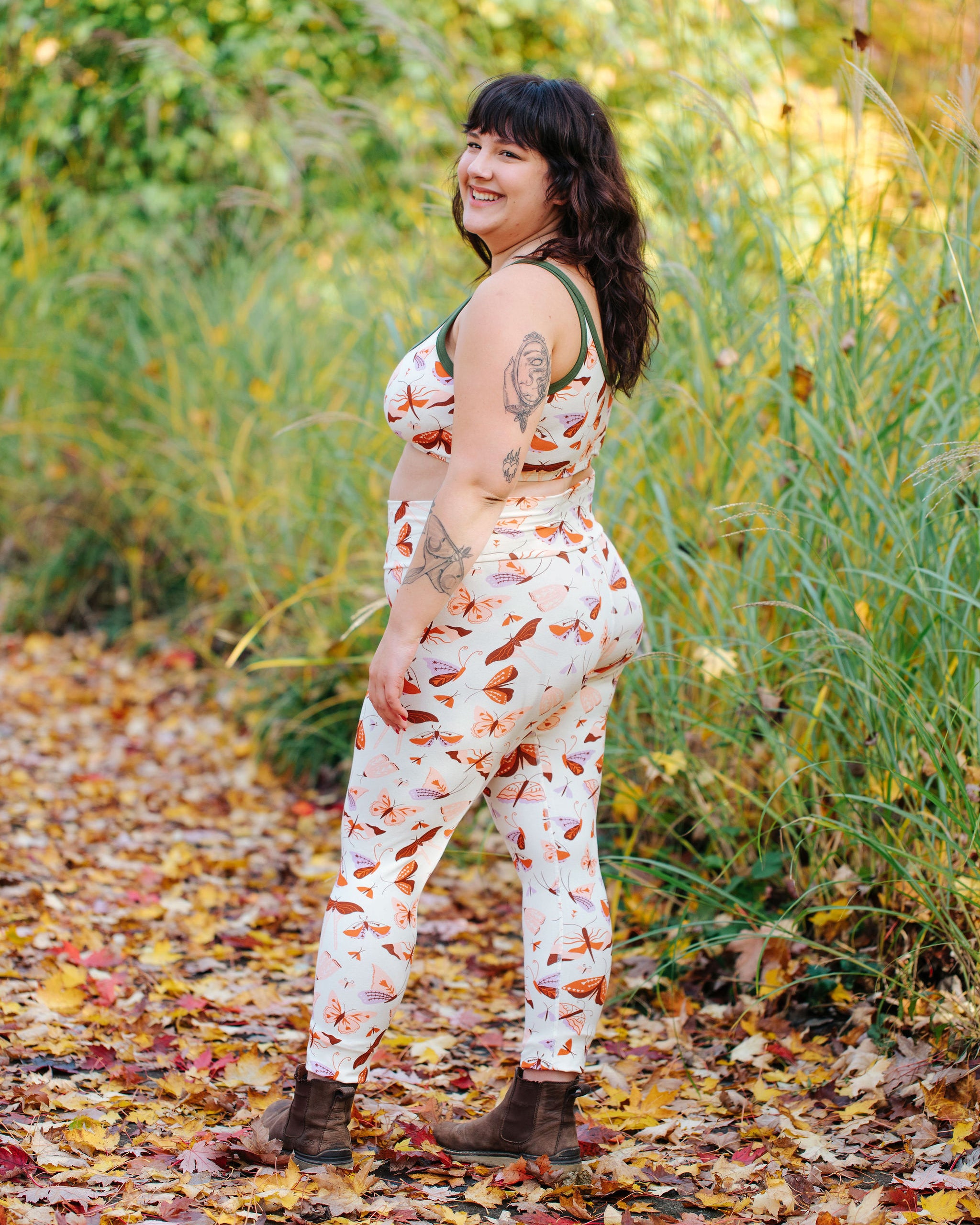 Model wearing Thunderpants Ankle Length Leggings and Longline Bra in Field Study: a moth print in red, orange, pink, and purple bound in green.