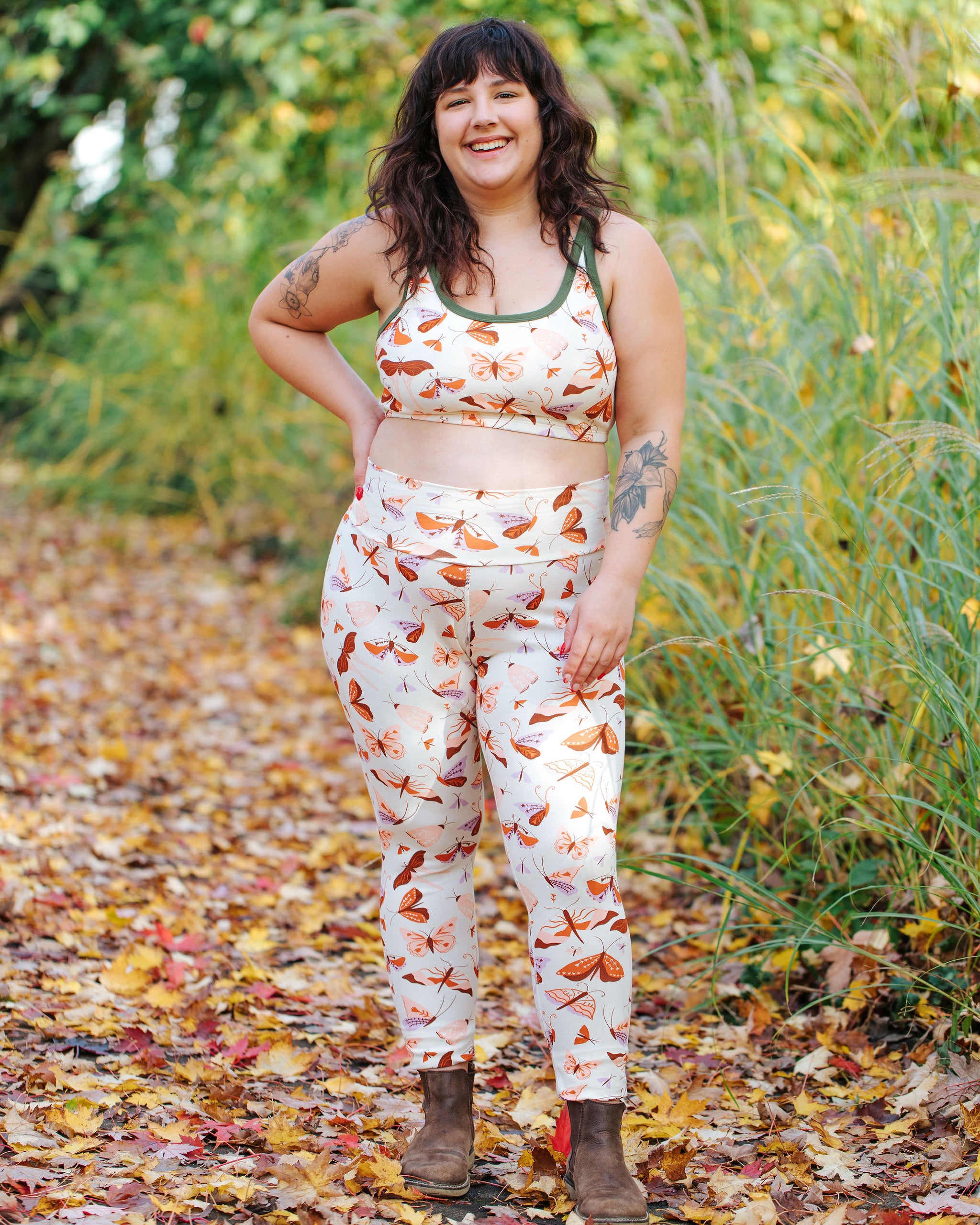 Model wearing Thunderpants Ankle Length Leggings and Longline Bra in Field Study: a moth print in red, orange, pink, and purple bound in green.