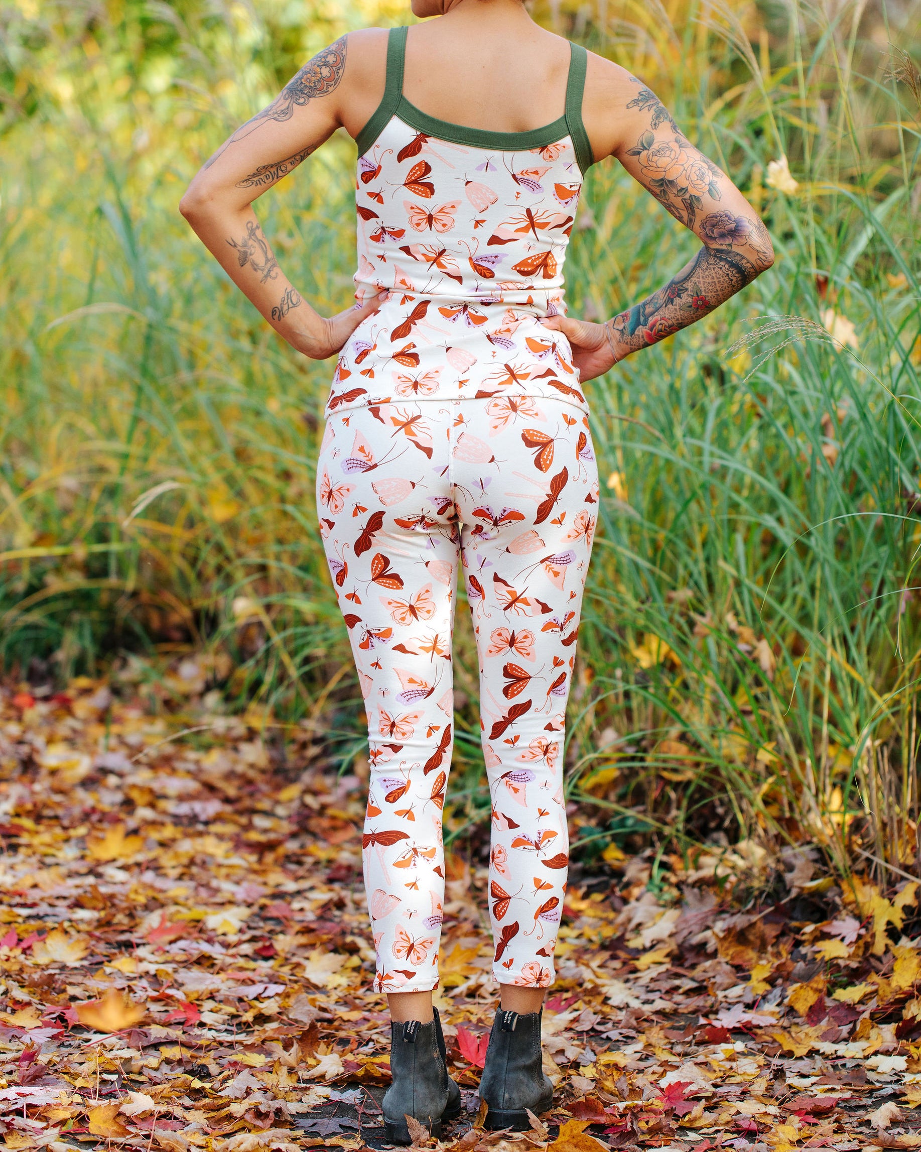 Model wearing Thunderpants Ankle Length Leggings and Cami in Field Study: a moth print in red, orange, pink, and purple bound in green.