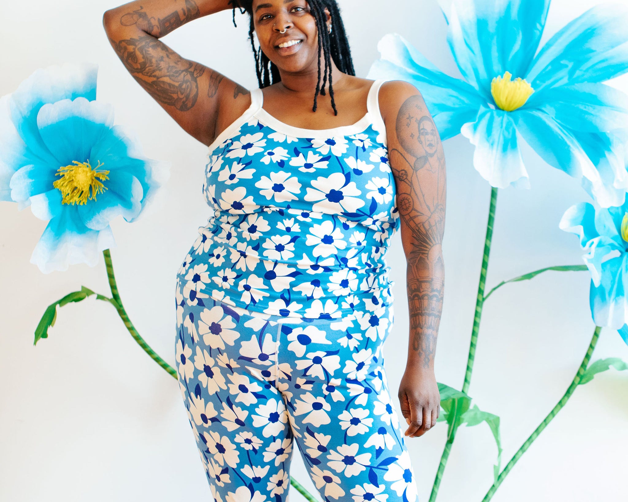 Model wearing Thunderpants Ankle Leggings and Camisole in Moody Blooms - white and blue flowers with blue background.