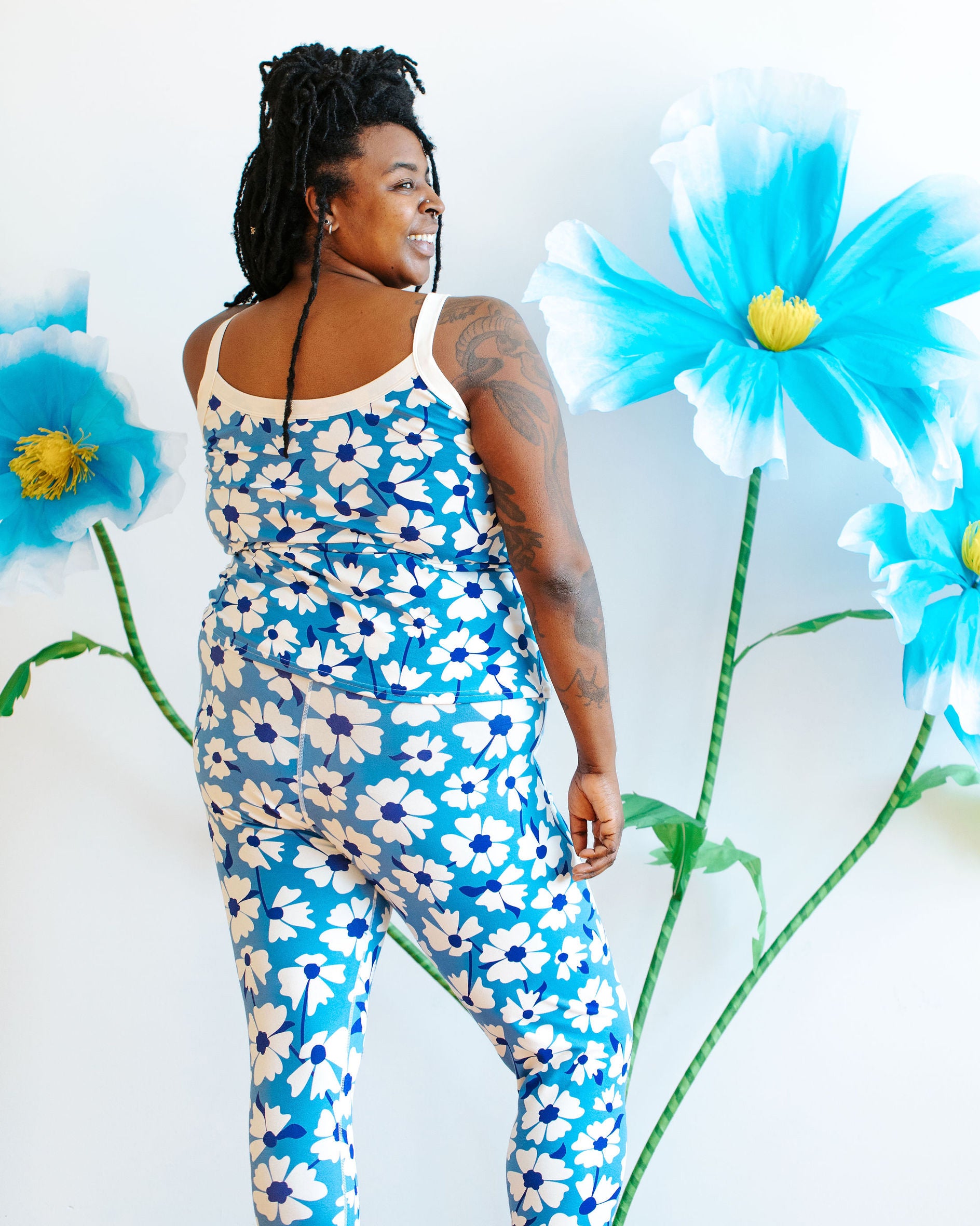 Model wearing Thunderpants Ankle Leggings and Camisole in Moody Blooms - white and blue flowers with blue background.