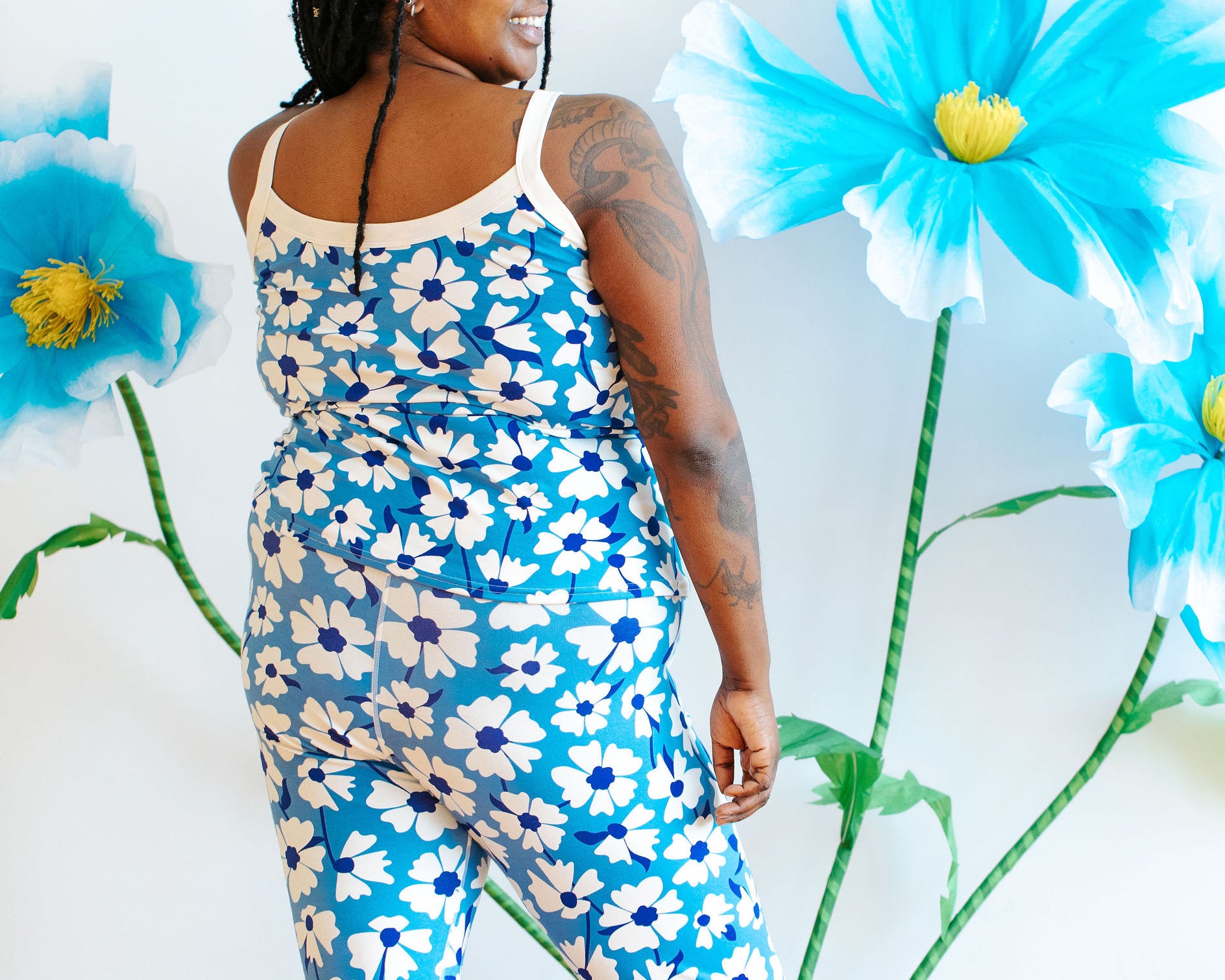 Model wearing Thunderpants Ankle Leggings and Camisole in Moody Blooms - white and blue flowers with blue background.